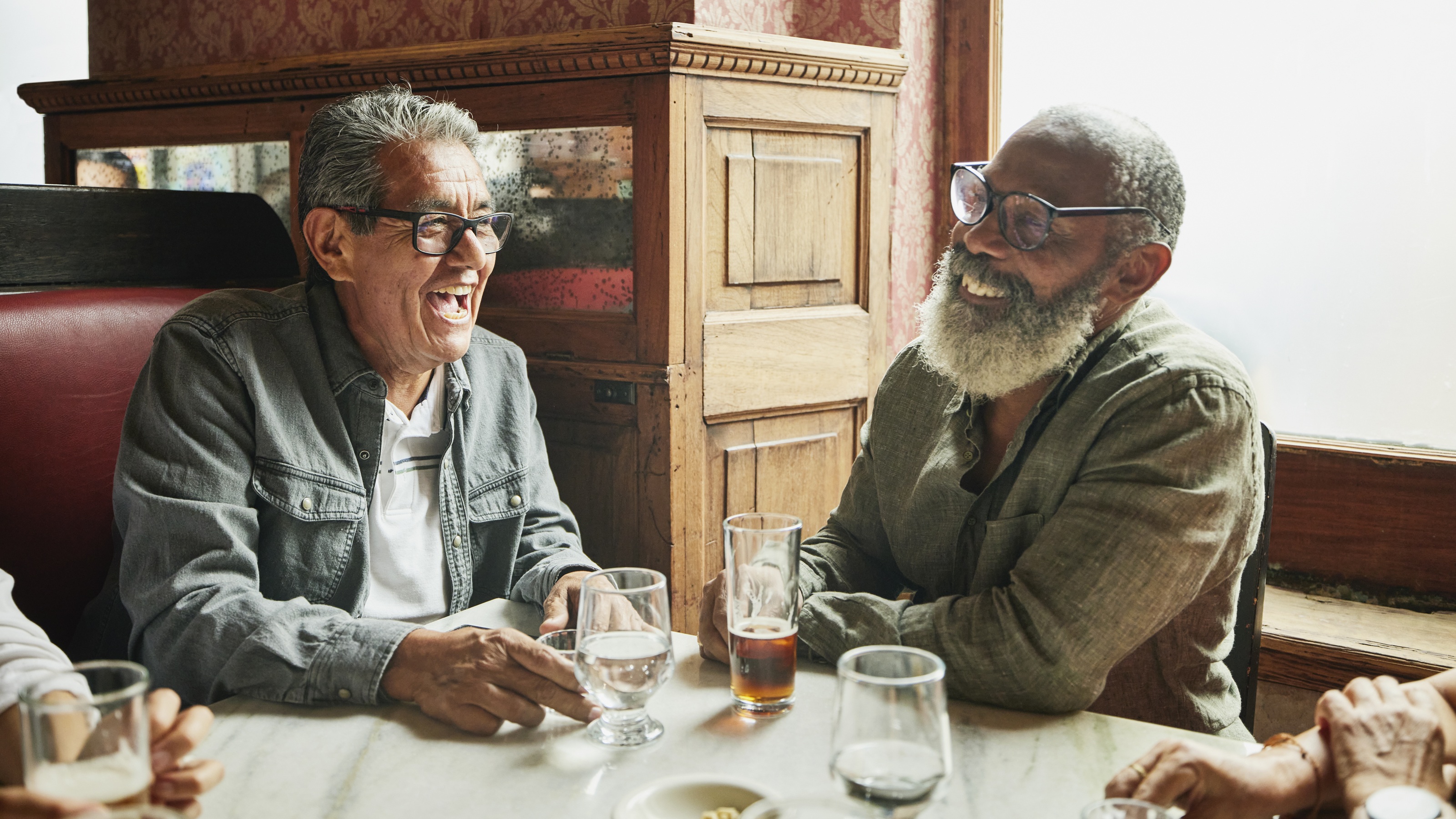 Deux hommes plus âgés rient ensemble dans un restaurant.