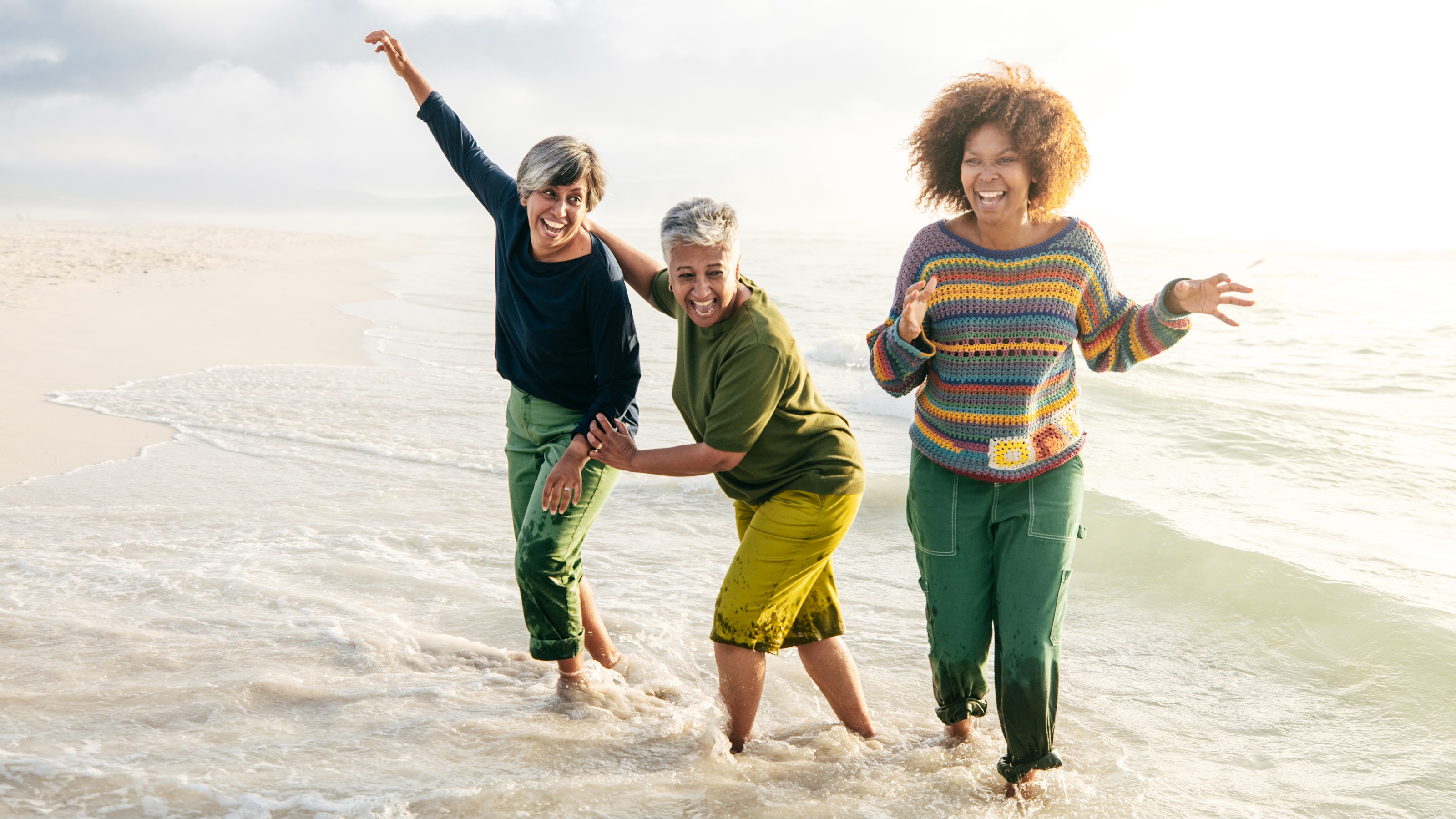 Trois femmes plus âgées rient et s'amusent sur la plage.