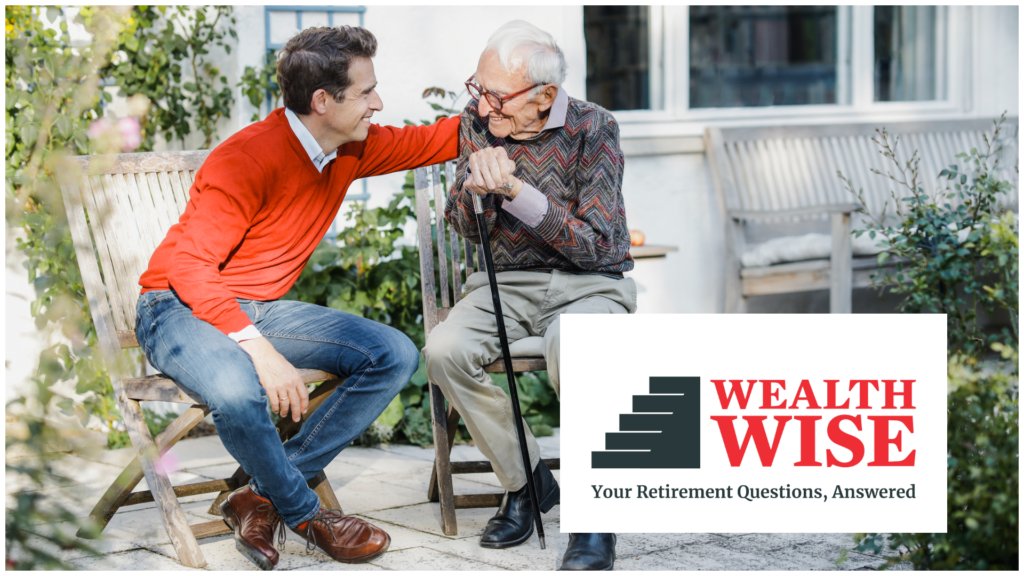 A man puts his elderly father on the back. His father is hunched over and holds a cane, but is smiling.