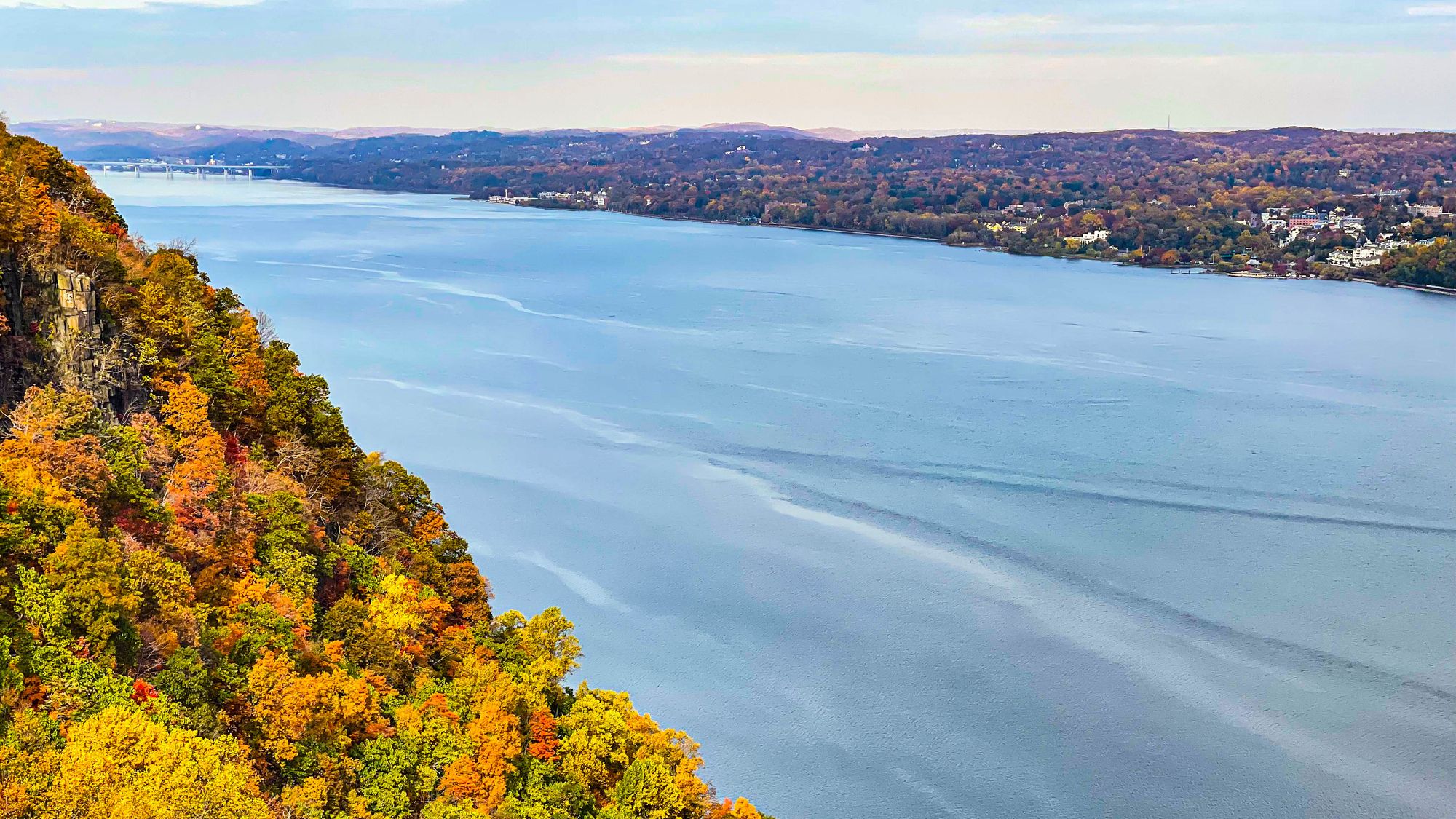 Vue des feuilles vertes, dorées et oranges des arbres sous les falaises de Palisade jouxtant la rivière Hudson sous un ciel spectaculaire au belvédère de la ligne d'état, Alpine, New Jersey, États-Unis.