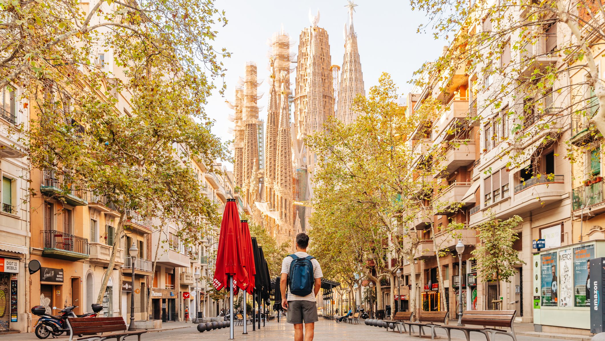 Un homme marche dans une rue vide de Barcelone en direction de la Sagrada Familia par une journée ensoleillée.