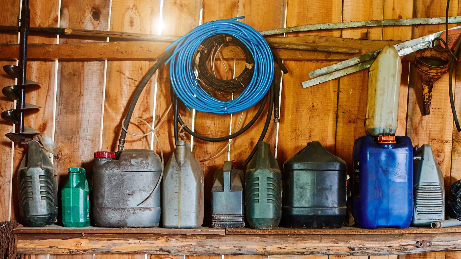 Un groupe de vieux bidons et cylindres se trouvent sur des étagères dans un hangar en bois