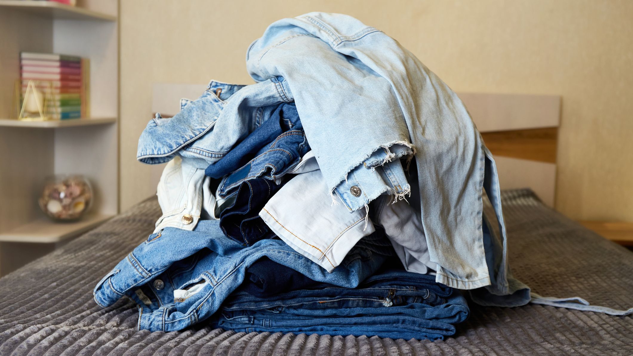 Une pile de vêtements en jean sur le lit.