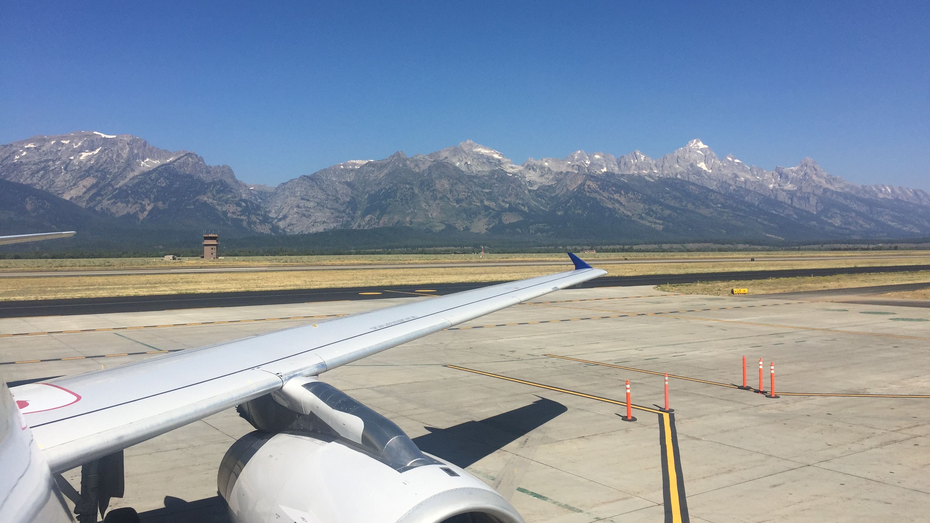 L'aile d'un avion sur une piste de l'aéroport de Jackson Hole, avec des montagnes en arrière-plan.