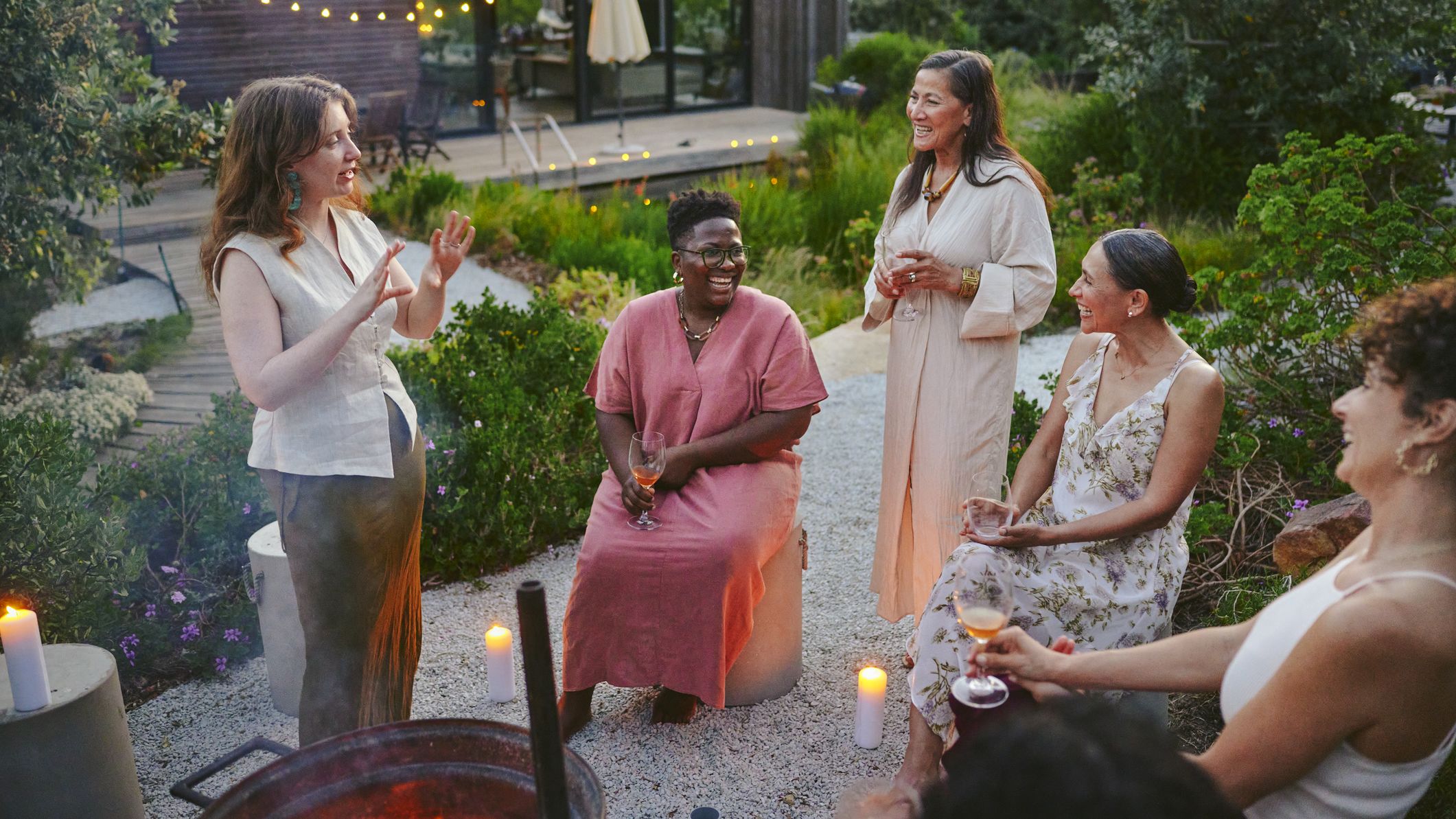 Diverses femmes riant autour d'un verre autour d'un foyer lors d'une garden-party