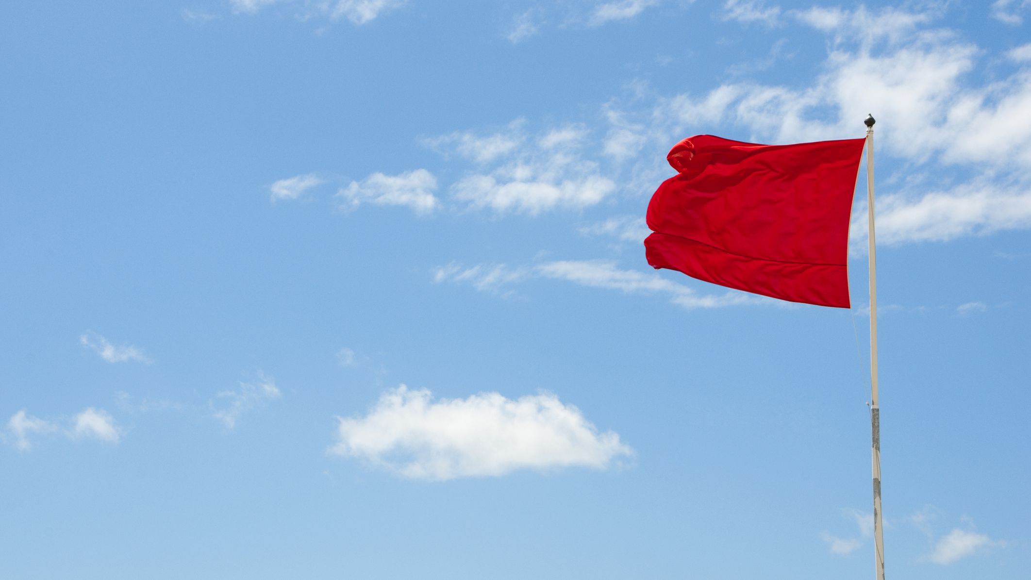 Drapeau rouge avertissant du danger contre un ciel bleu