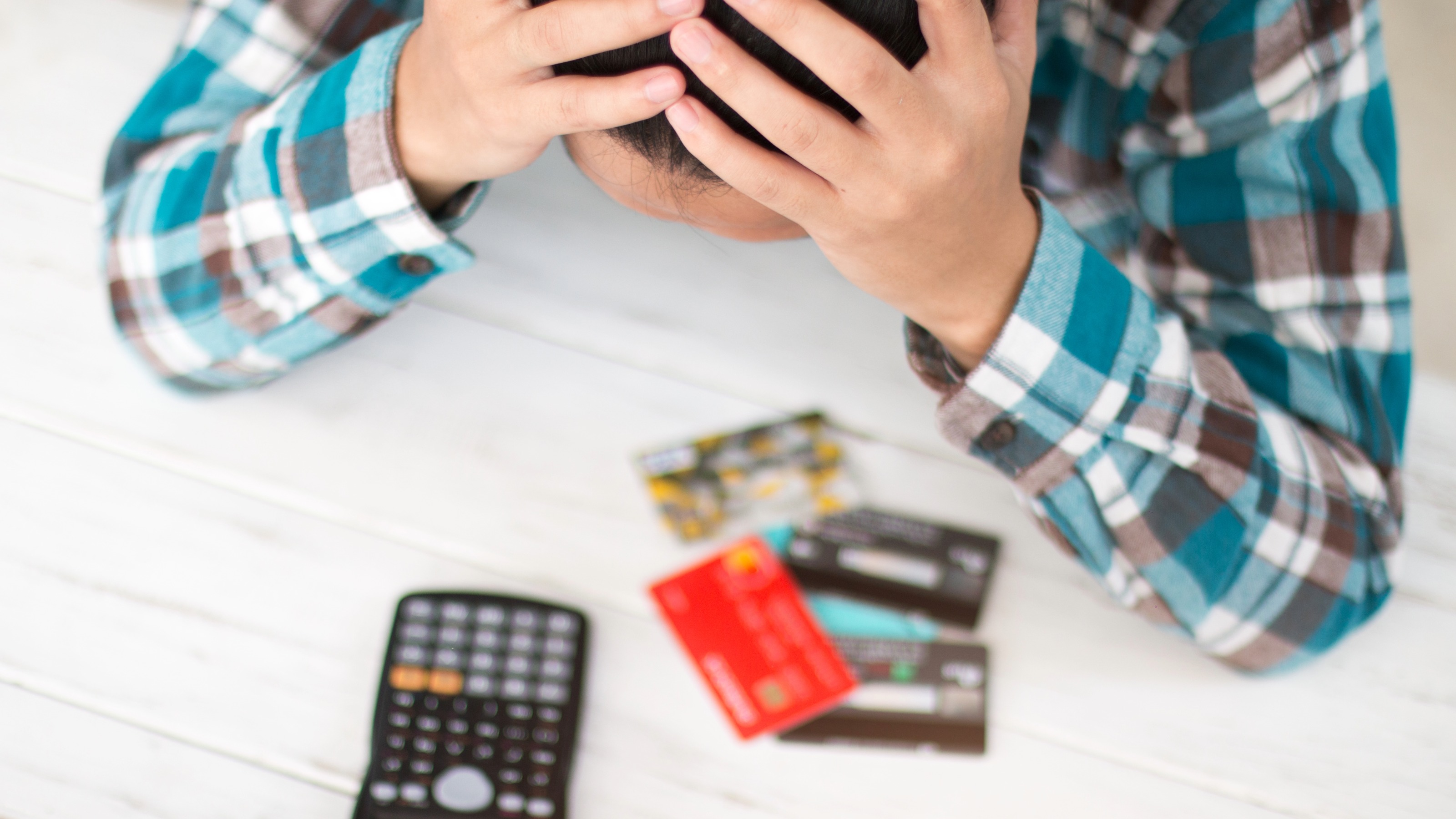 L'homme tient la tête dans les mains pendant qu'il regarde les cartes de crédit et la calculatrice
