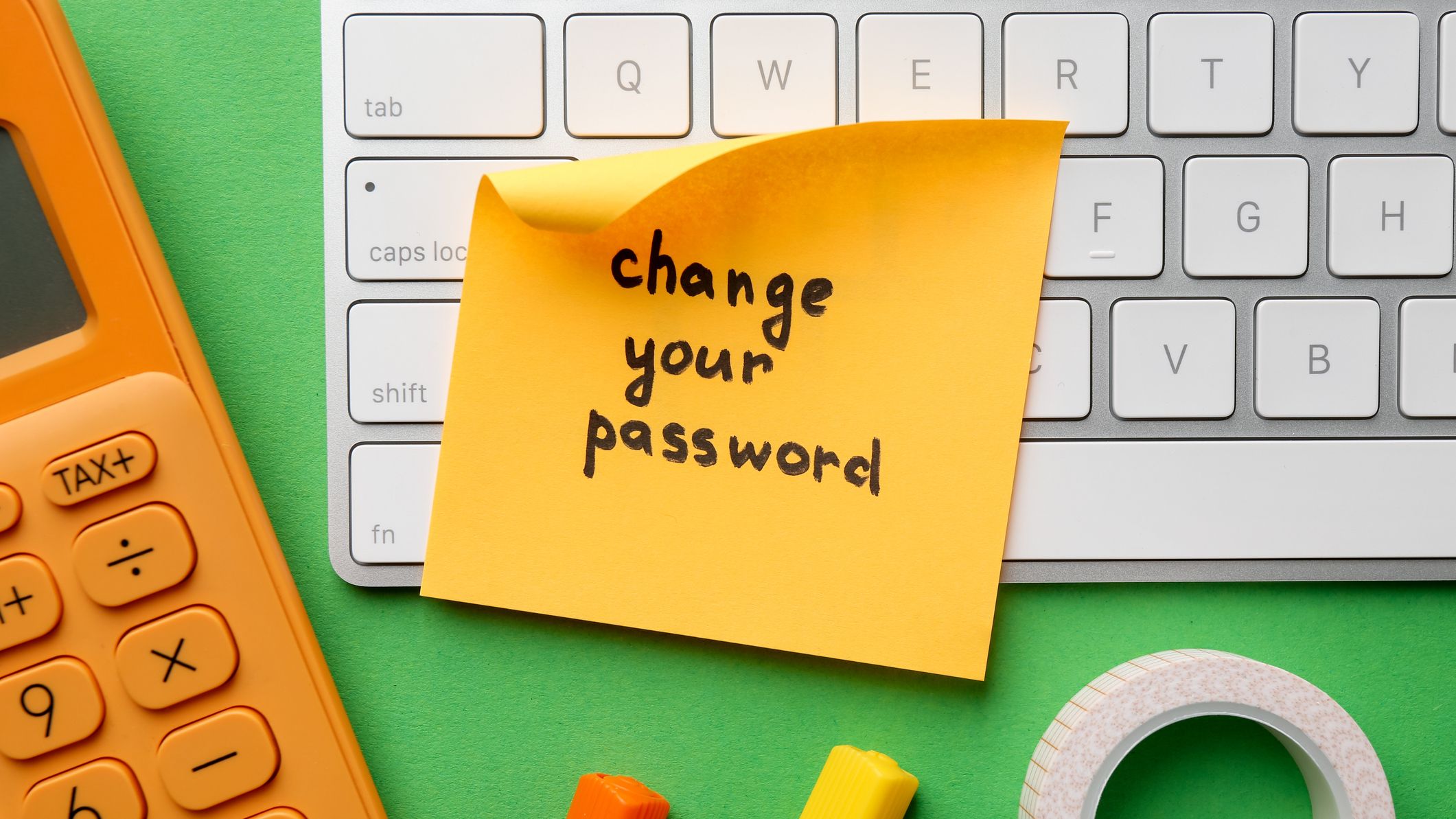 Un post-it avec la phrase "Changez votre mot de passe" écrit dessus entouré d'un clavier et d'une calculatrice.