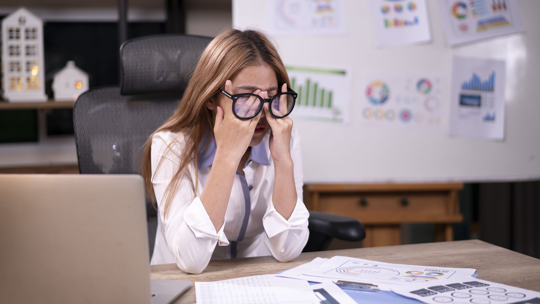 une femme frustrée se frotte le nez après avoir parcouru des documents financiers