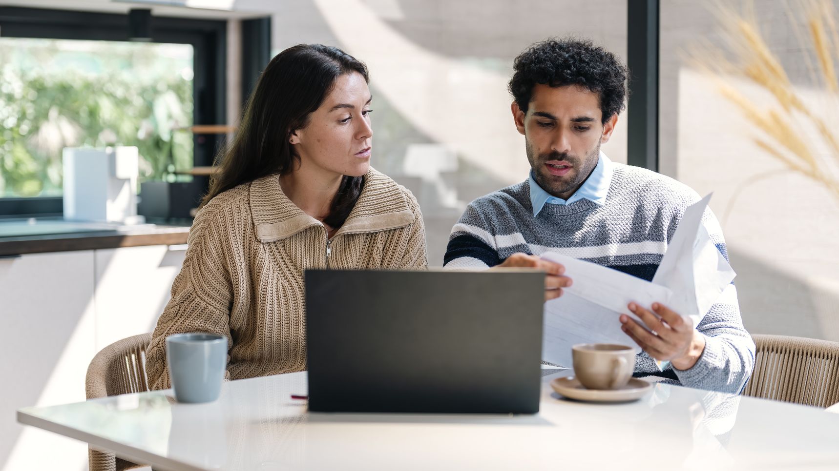 un couple examine ses finances à une table de cuisine