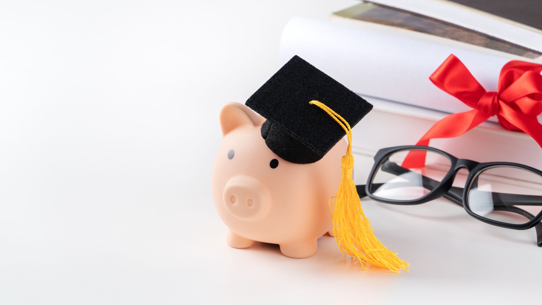 Une tirelire coiffée d'une casquette de graduation.