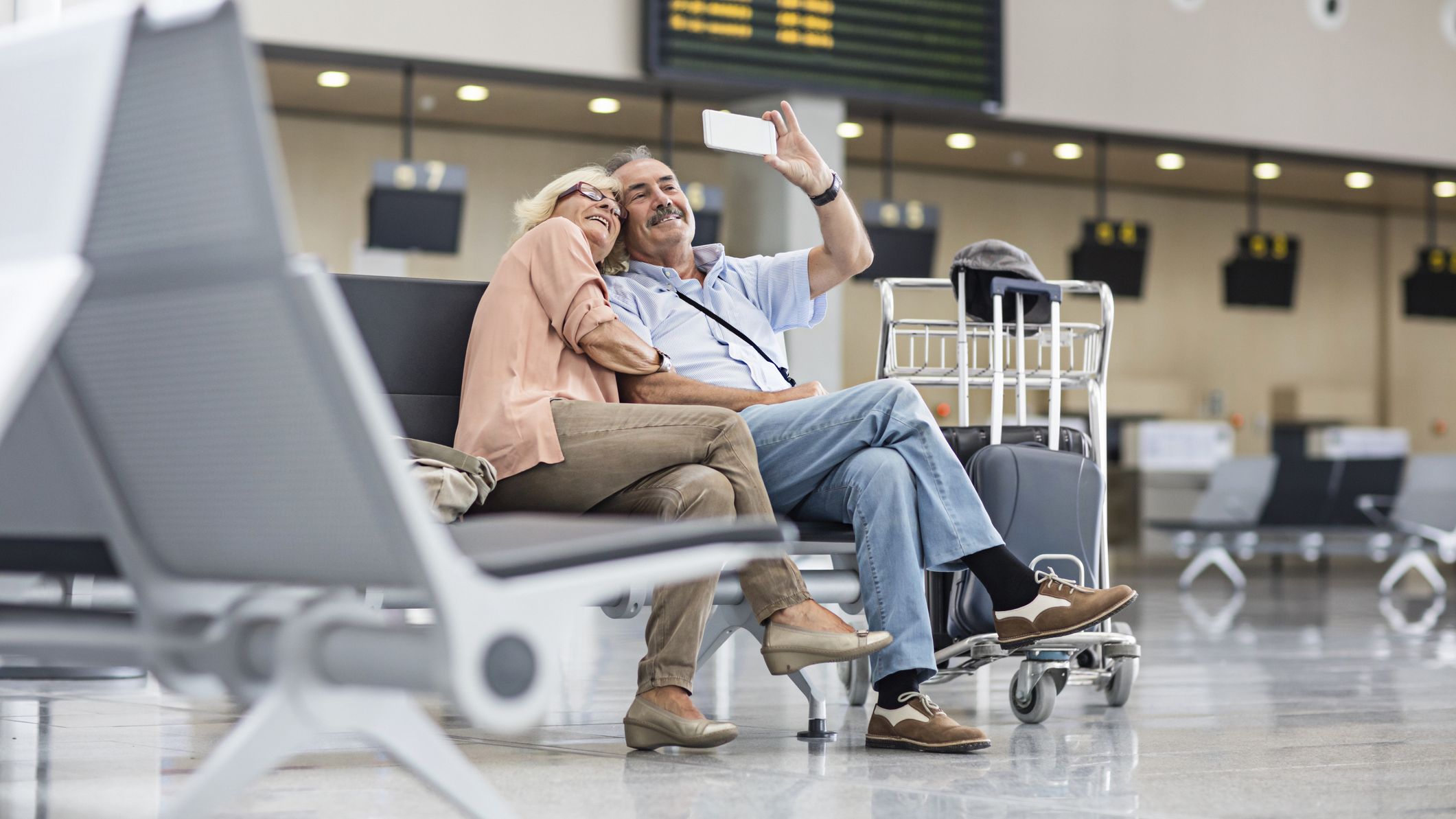 Couple senior prenant un selfie à l'aéroport en attendant de s'enregistrer à l'aéroport pour leurs vacances.