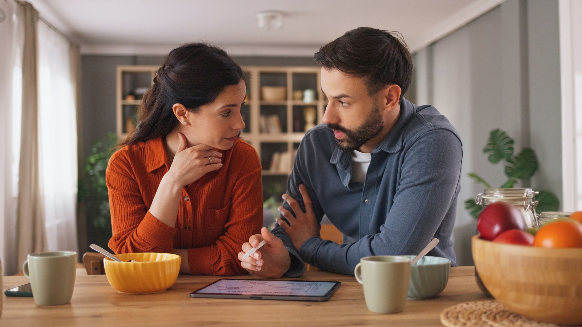 Couple discutant des finances au petit-déjeuner à la maison à l'aide d'une tablette numérique