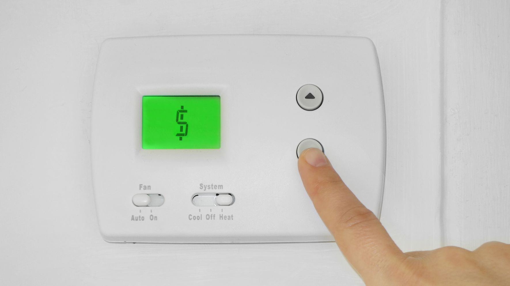 Doigt appuyant sur un bouton d'un thermostat qui affiche un signe dollar, indiquant l'augmentation des coûts énergétiques.