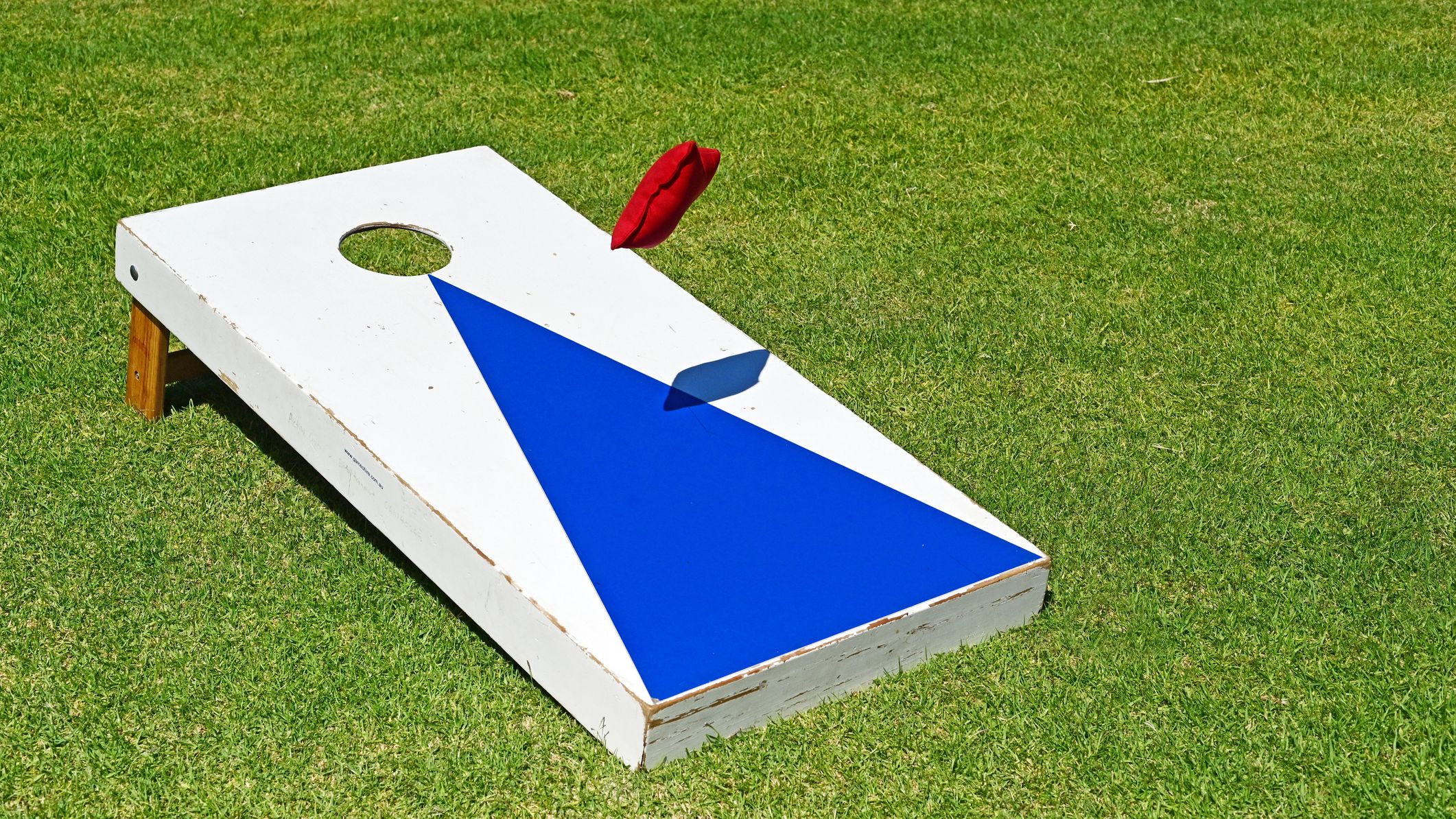 Un sac jeté vers une planche de cornhole.