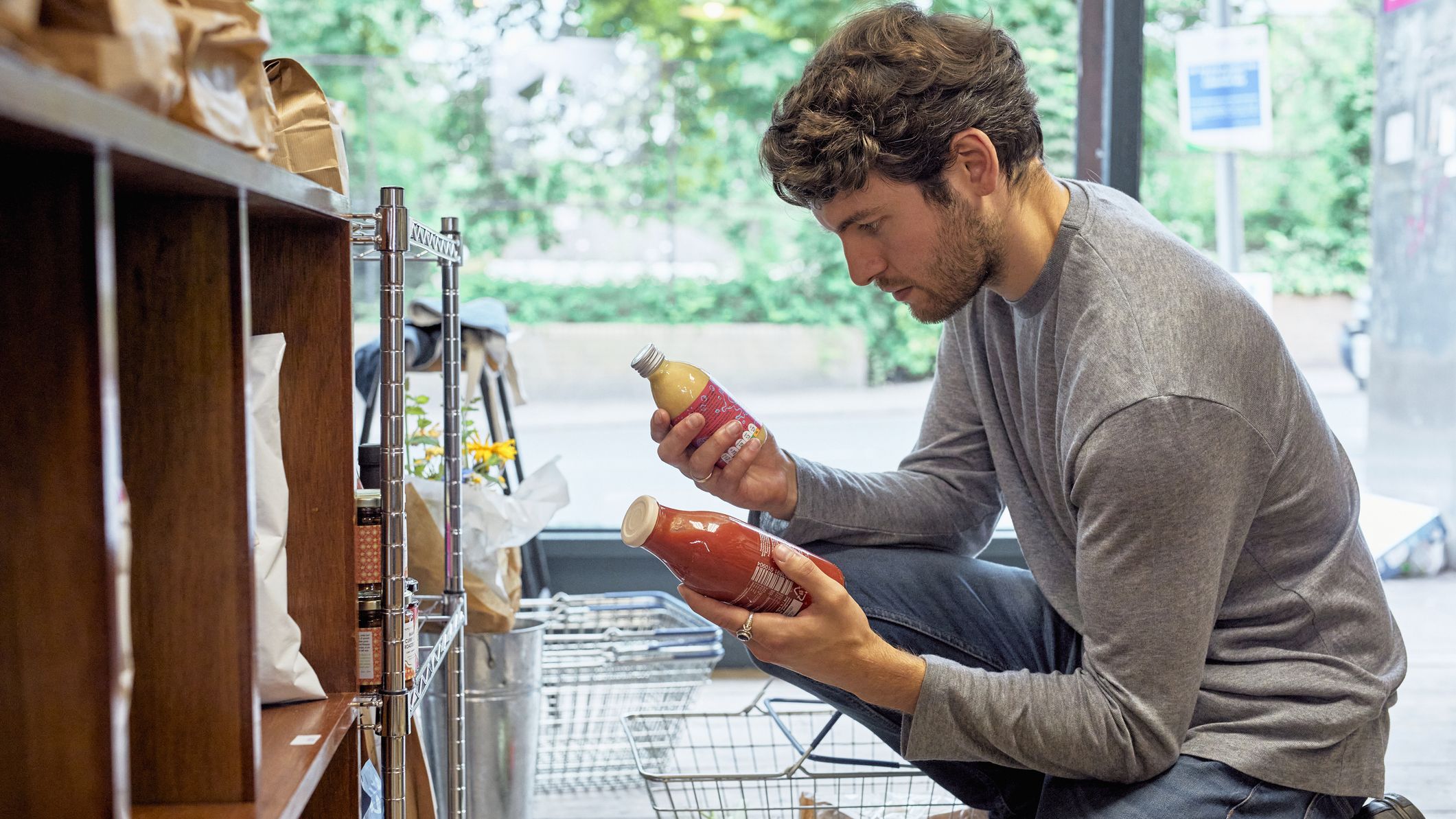 un homme compare deux bouteilles de jus