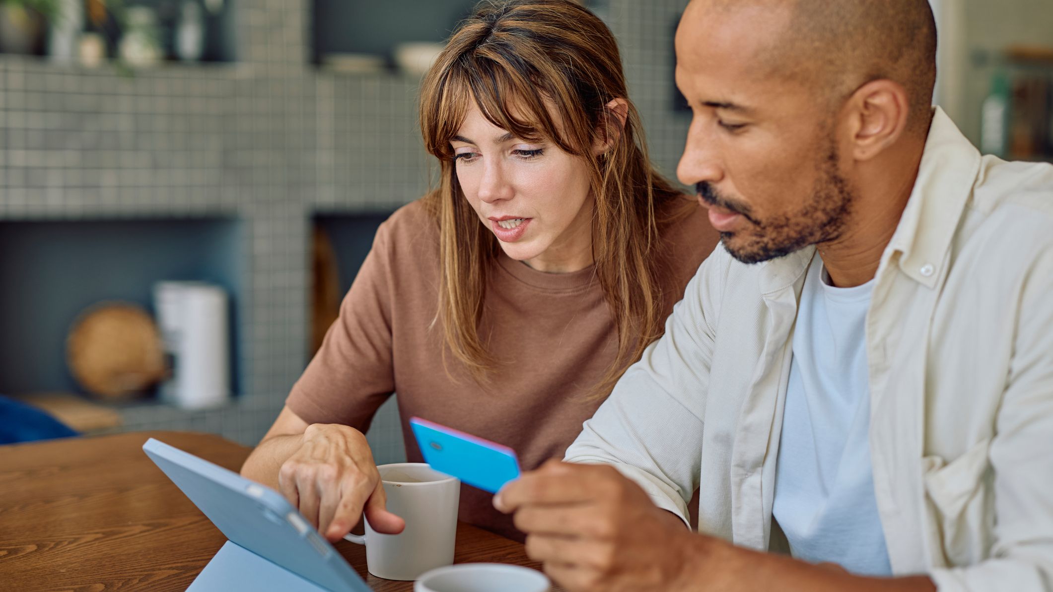 Couple ciblé utilisant une tablette numérique et une carte de crédit