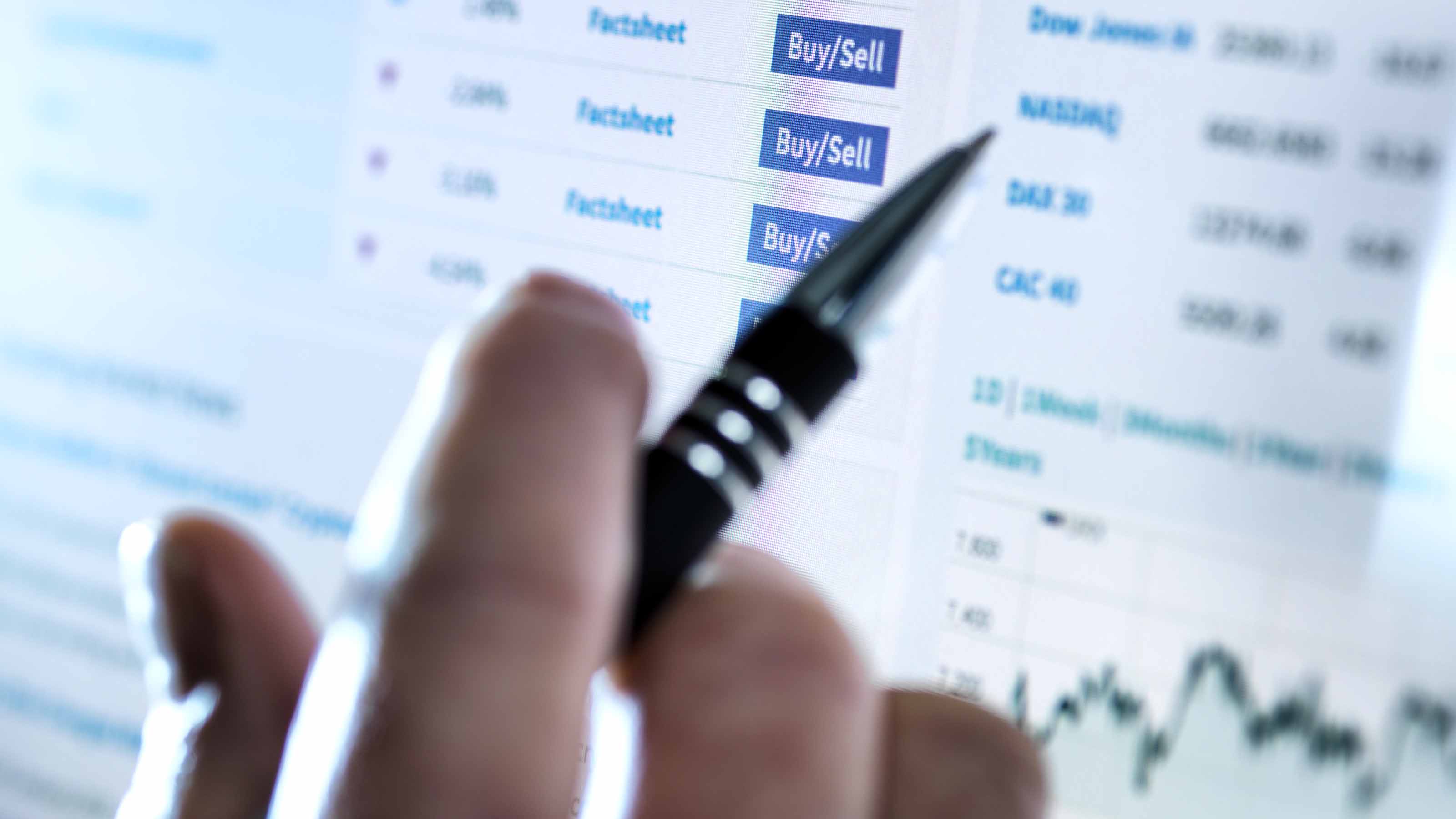 gros plan d'une personne avec un stylo achetant et vendant des actions en ligne