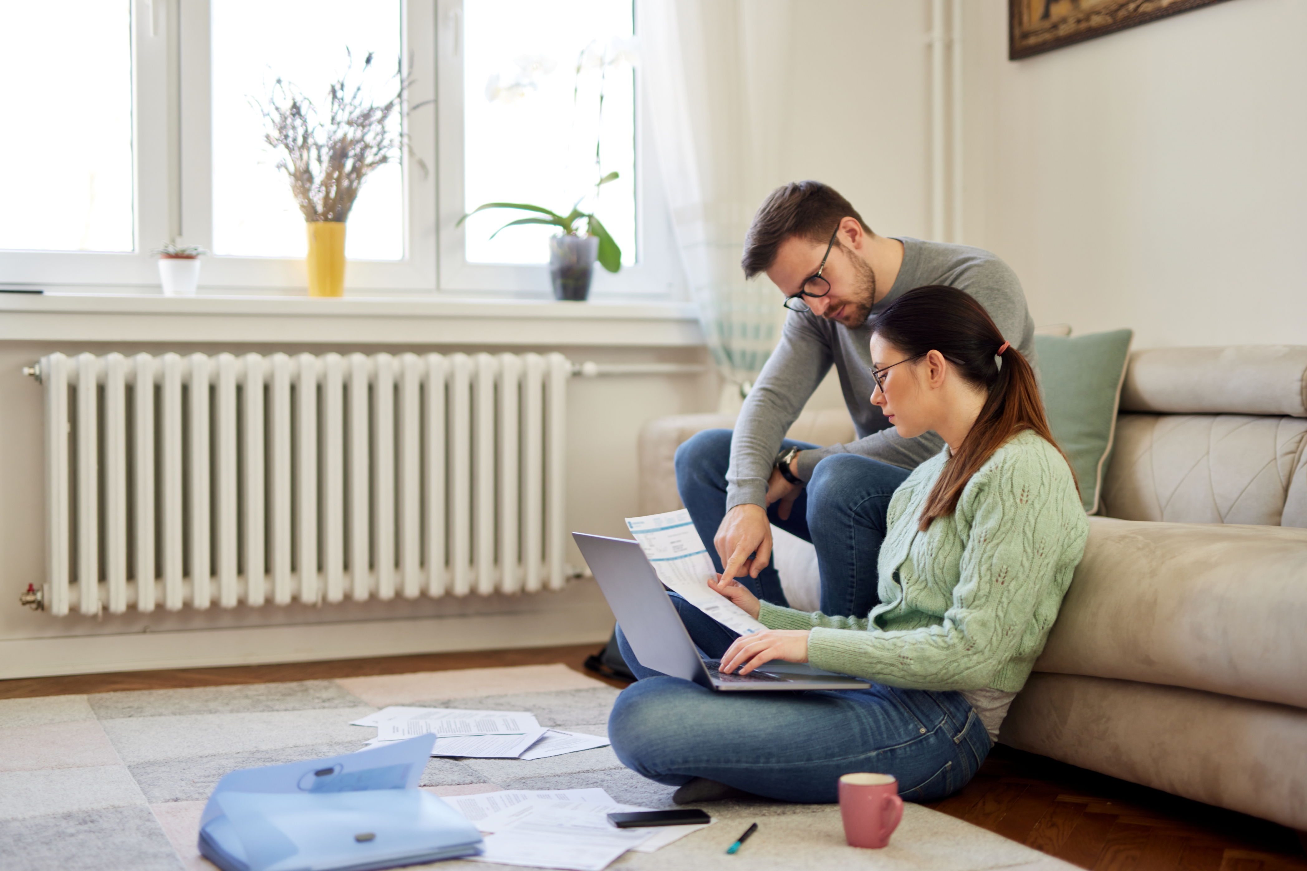 Un jeune couple est assis dans son salon et examine des documents et discute de son budget.
