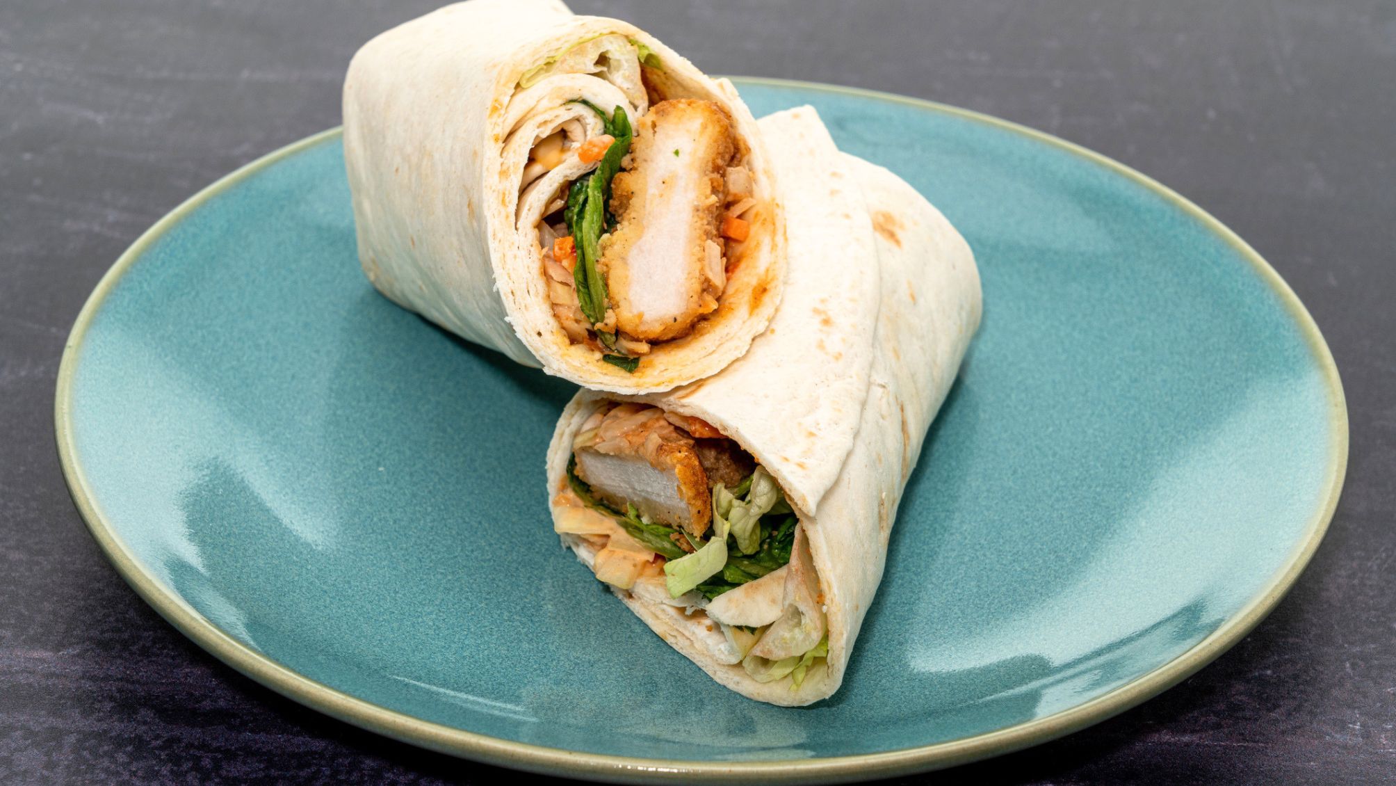Un wrap au poulet sur une assiette turquoise.