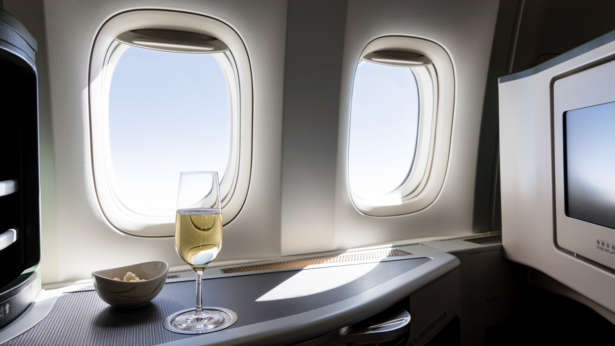 Un verre de vin et un petit bol de collations sur une table en classe affaires ou en première classe d'un avion.