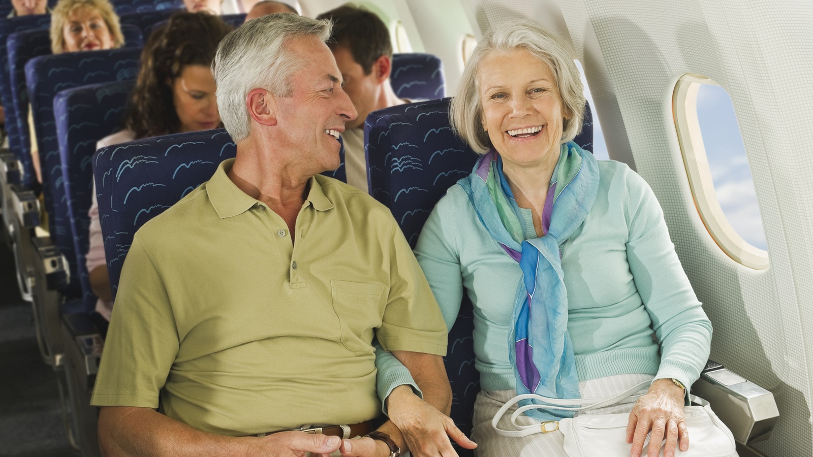 D'âge mûr dans un avion, assis bras dessus bras dessous.