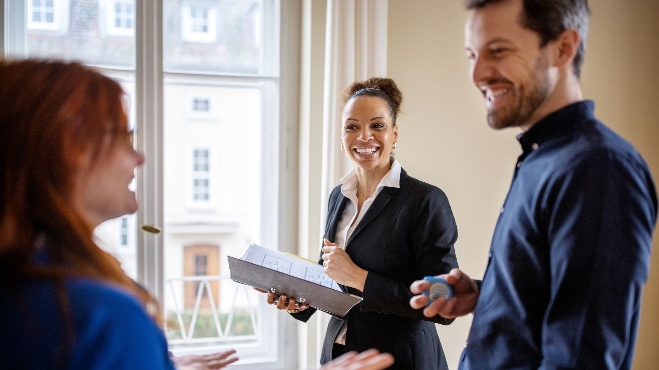 Heureux couple regardant une maison avec un agent immobilier