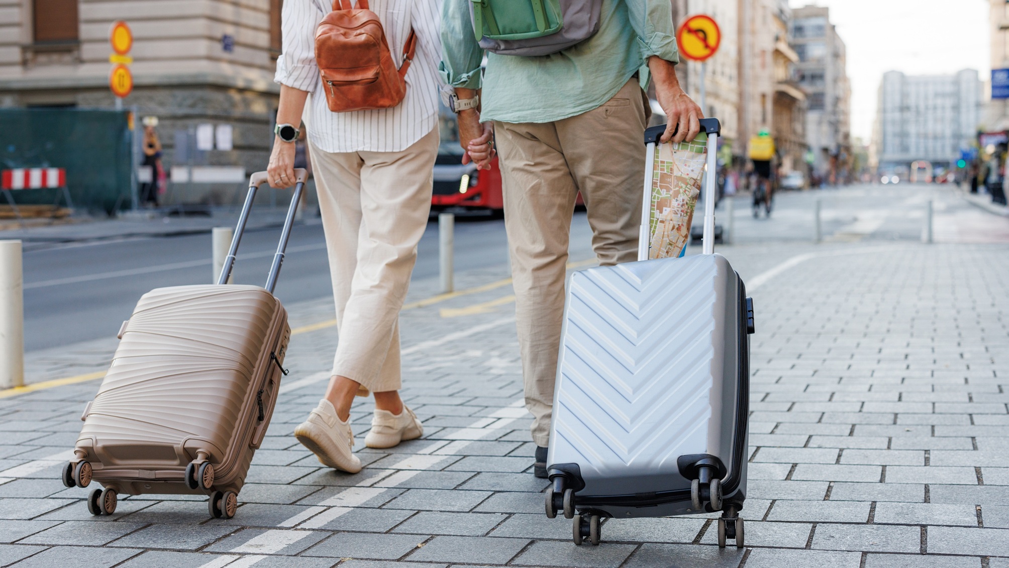 Un couple marchant dans une rue de la ville, chacun tirant une valise.