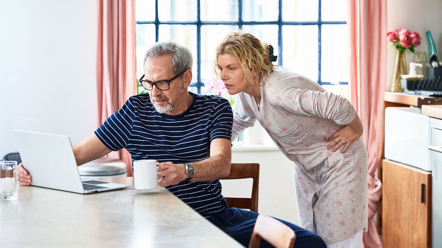 Un couple d'âge mûr dans leur cuisine a l'air inquiet tout en examinant ses finances sur son ordinateur portable.