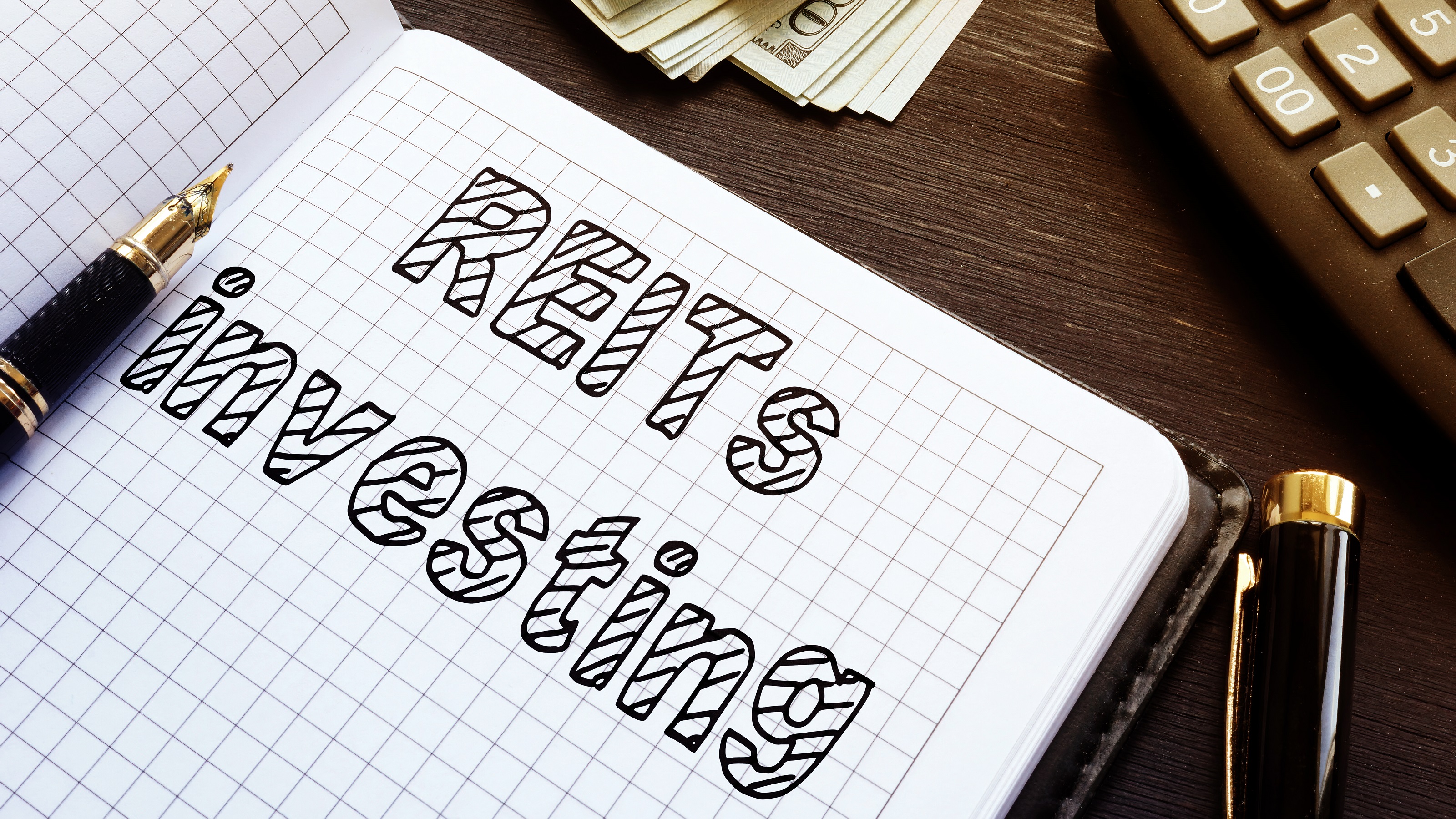 L'investissement dans les REIT est écrit sur du papier millimétré dans un cahier.