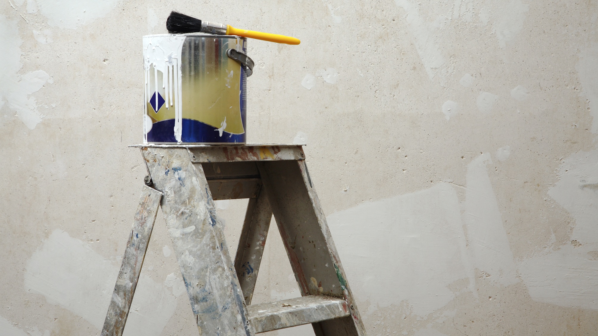 Une échelle avec un pot de peinture et un pinceau sur le dessus.
