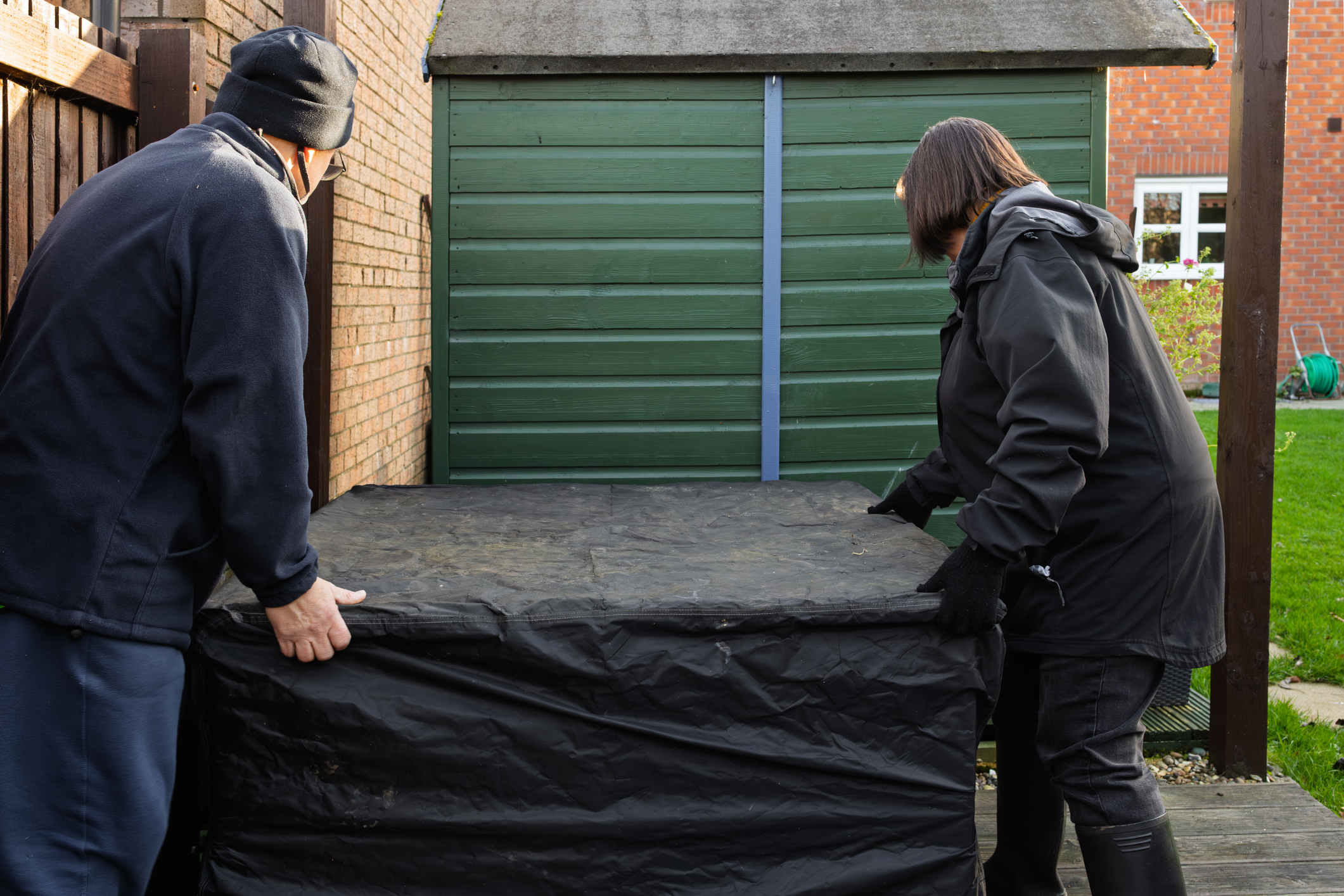 Un couple d’âge mûr déplace un foyer couvert loin de leur maison.