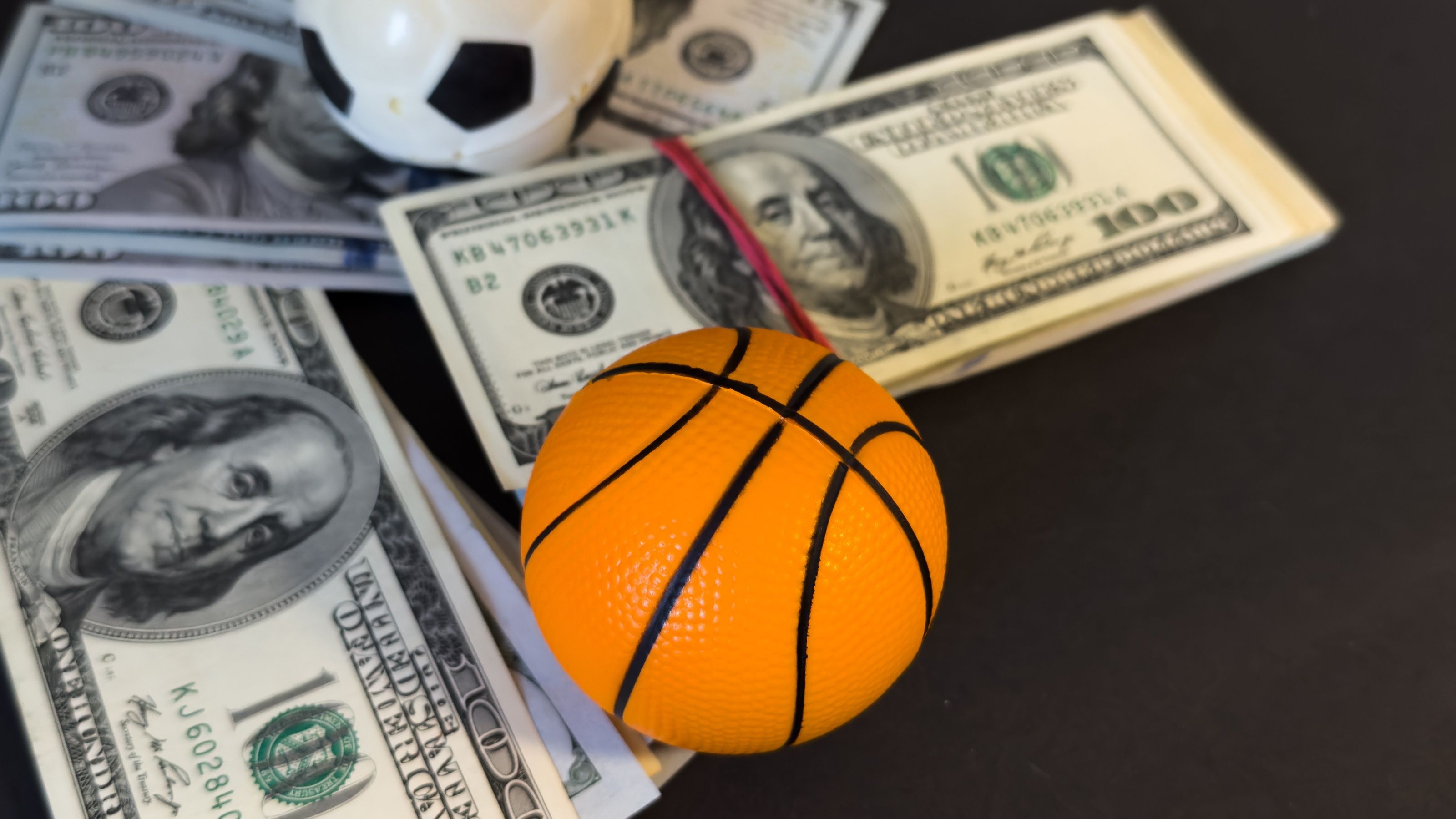 Cash assis sous un ballon de football et un ballon de basket.