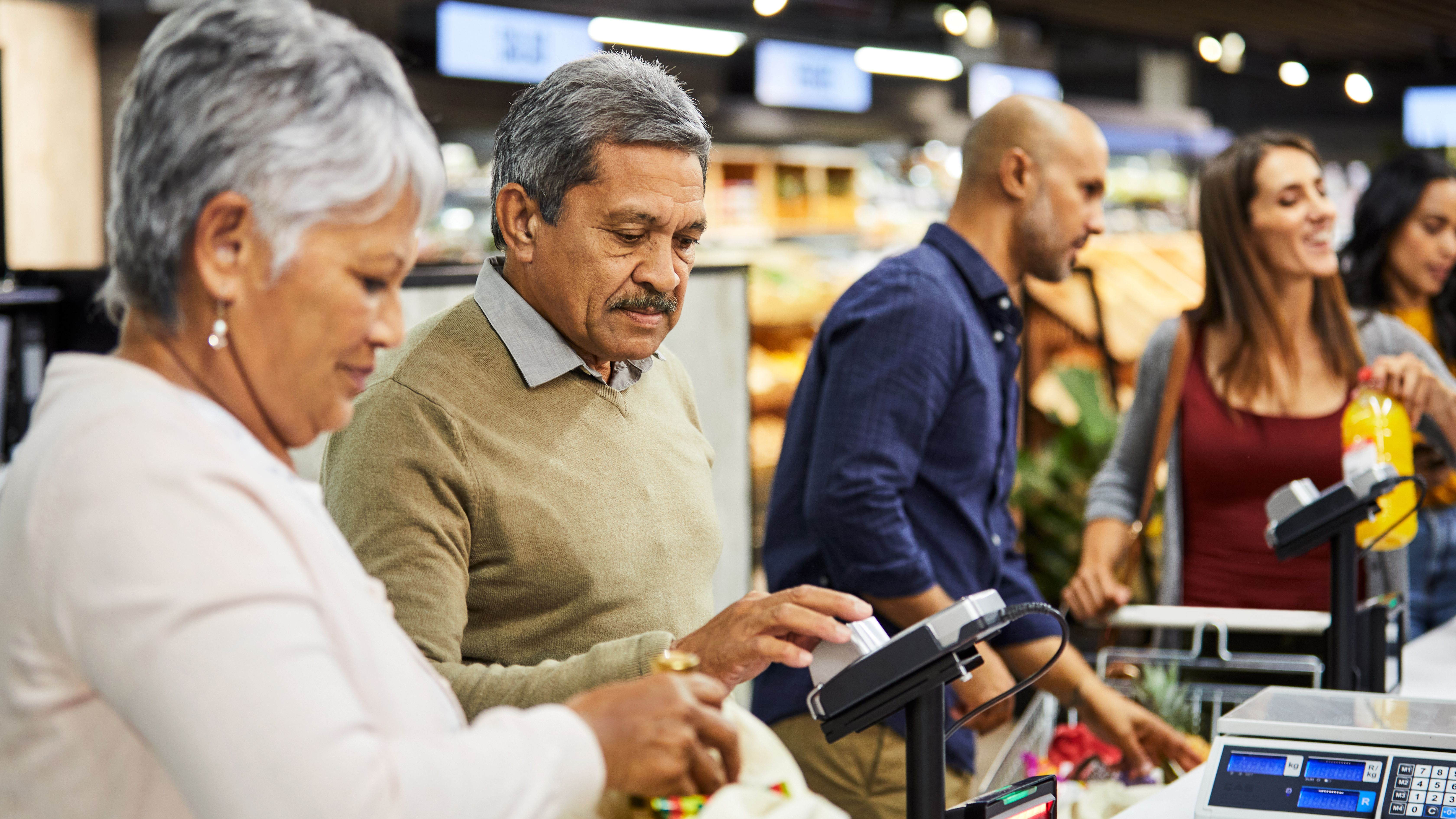 Photo d'un couple de personnes âgées payant leurs courses dans un supermarché