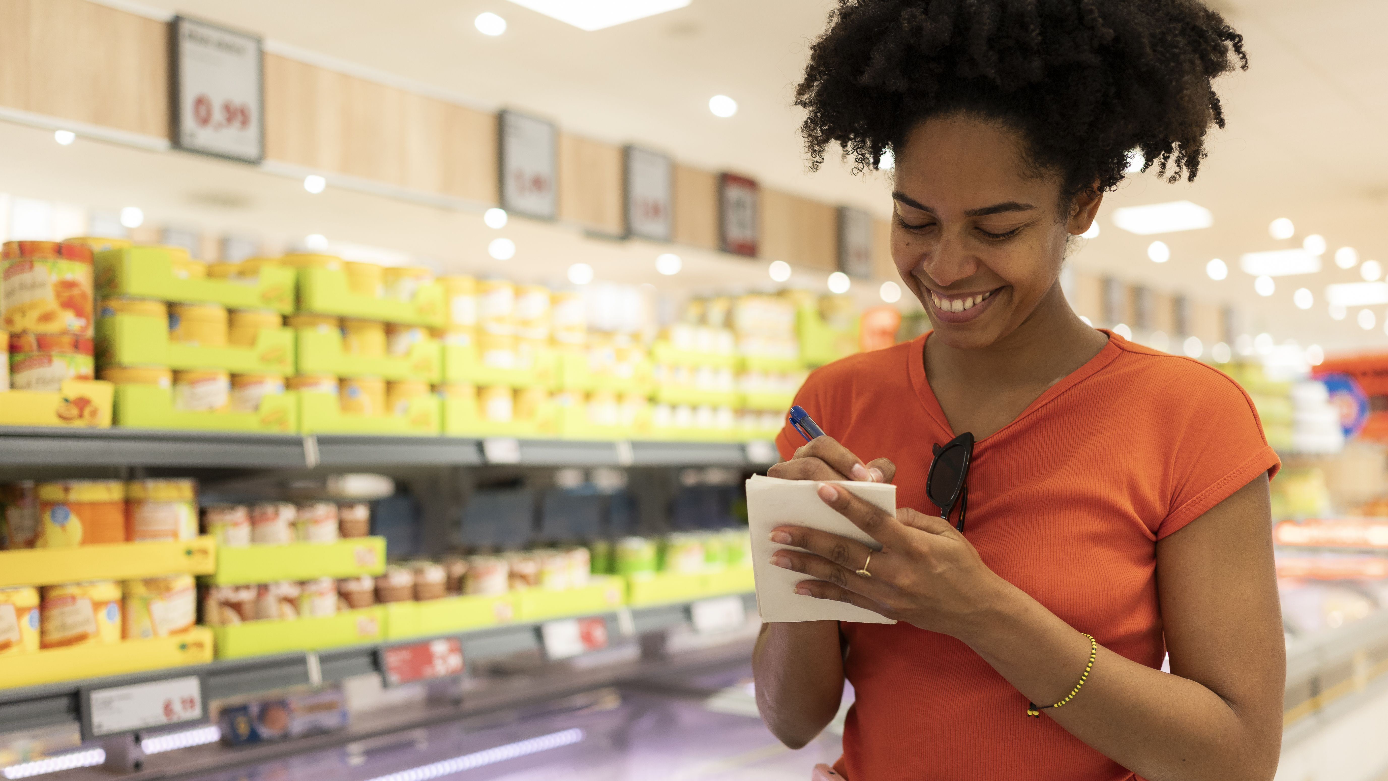 Jeune femme adulte vérifiant la liste d'épicerie au supermarché