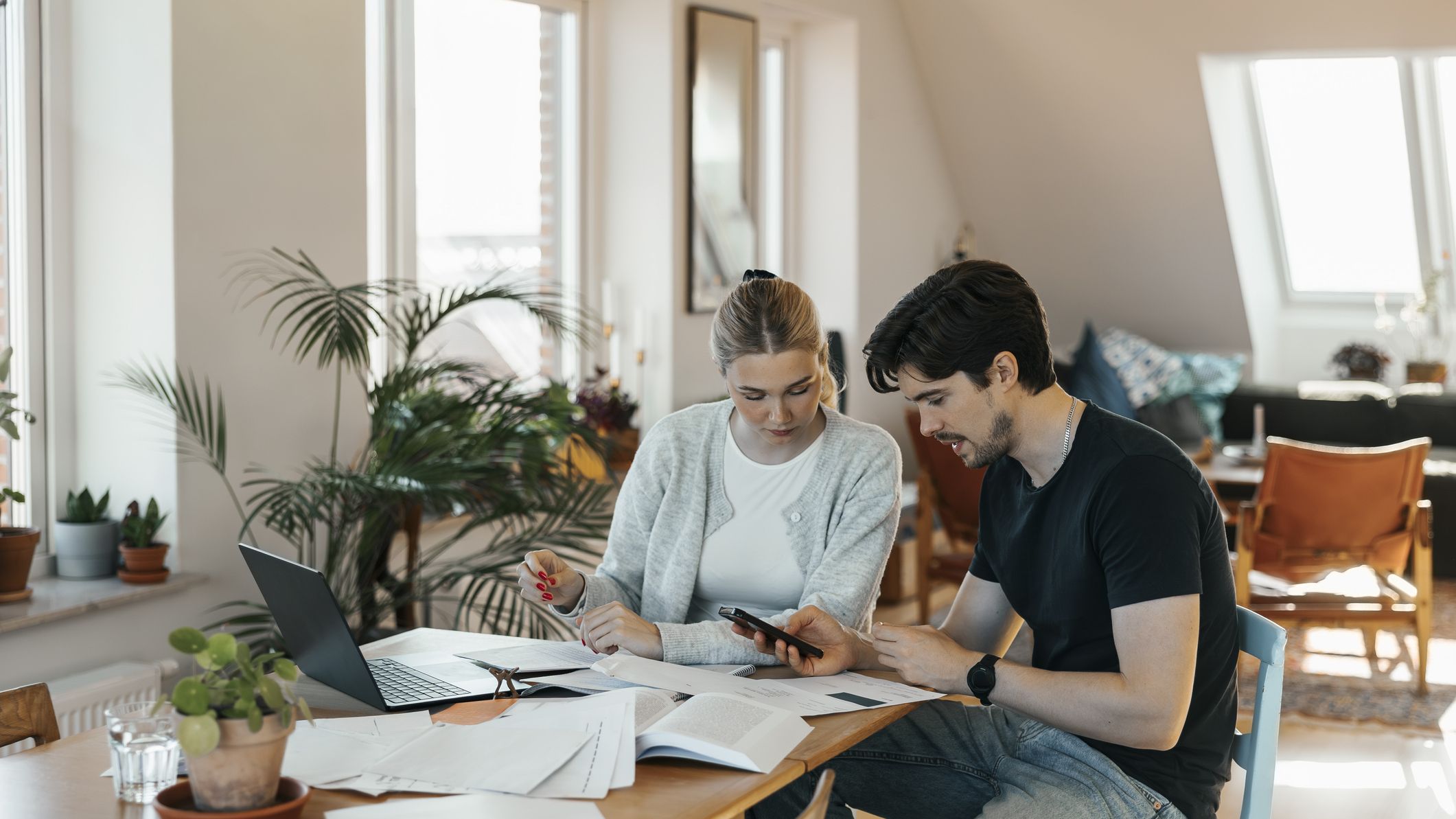 Jeune couple calculant ses économies tout en faisant la comptabilité à la maison