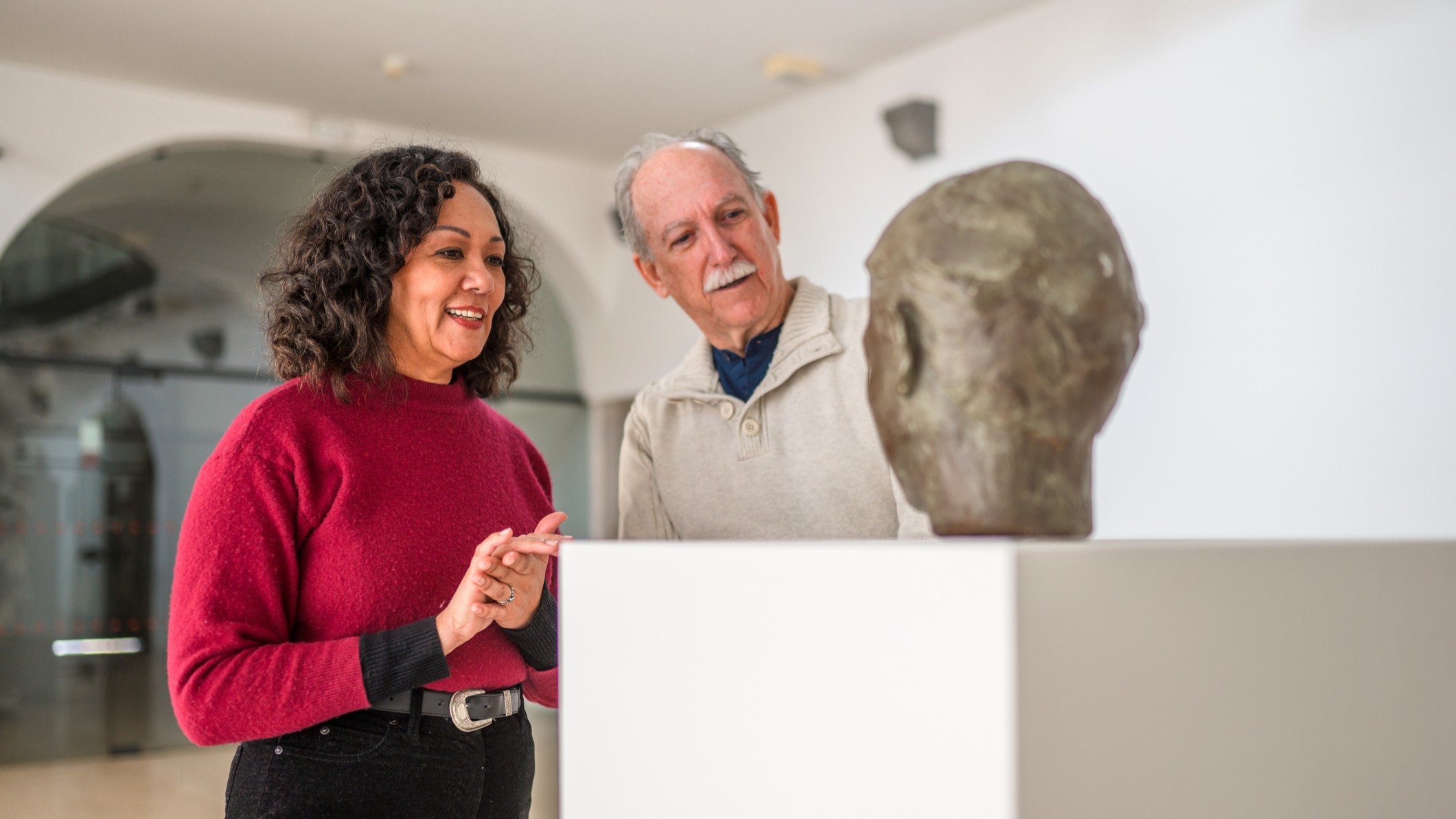 Une femme et un homme plus âgés voient une sculpture. Ils peuvent être en couple ou la femme peut être un guide expliquant la pièce.
