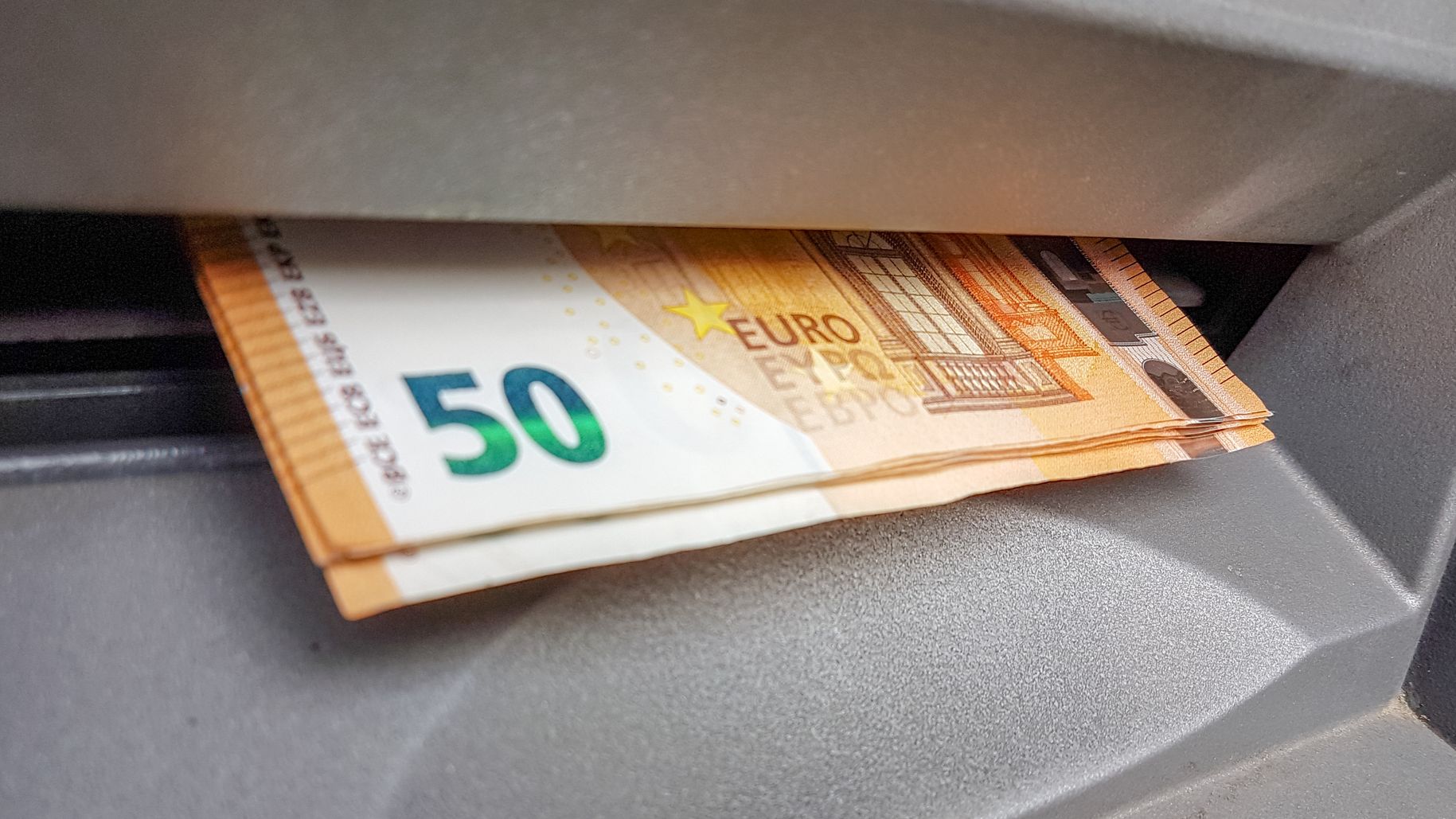 Des euros qui sortent d'un distributeur automatique.