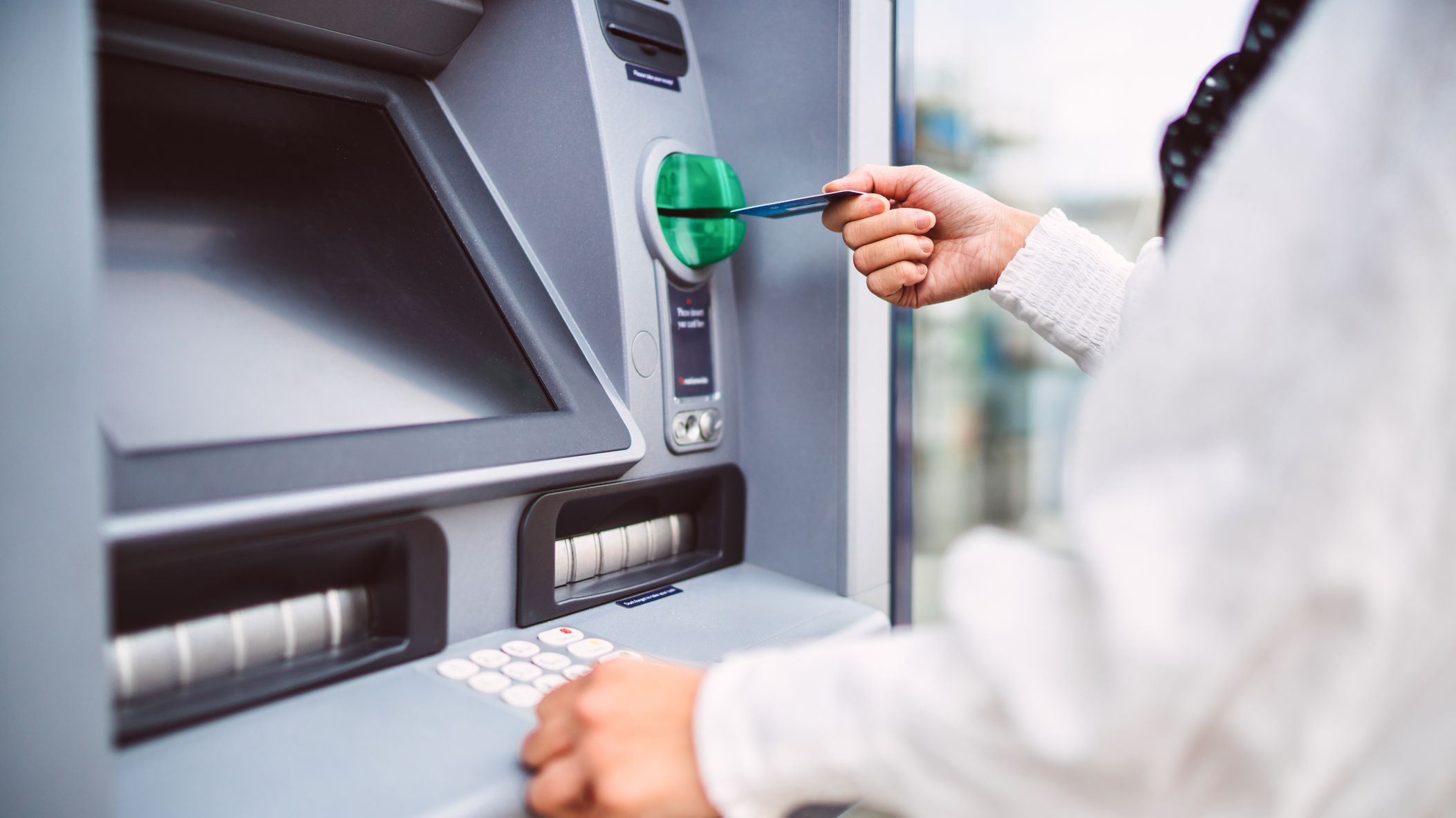 Femme insérant une carte bancaire dans un distributeur automatique
