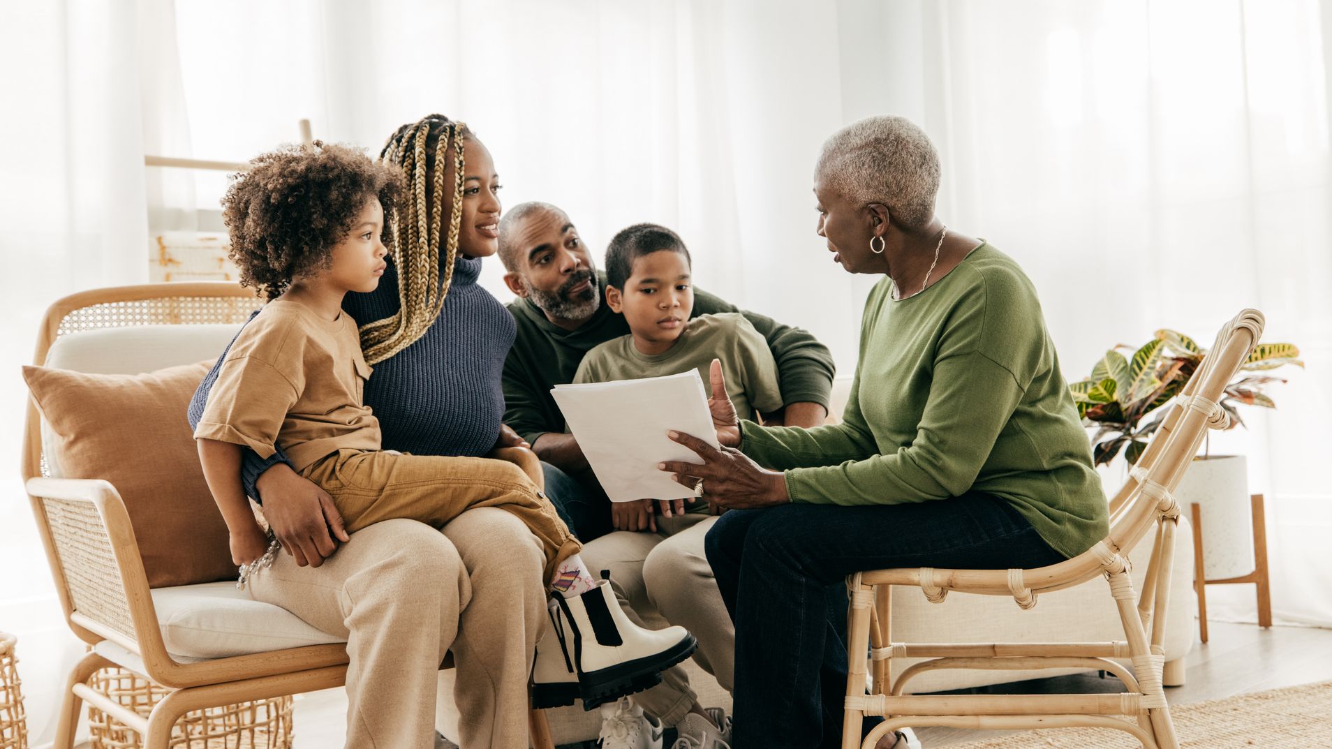 Une femme âgée examine les documents financiers avec sa famille dans son salon.