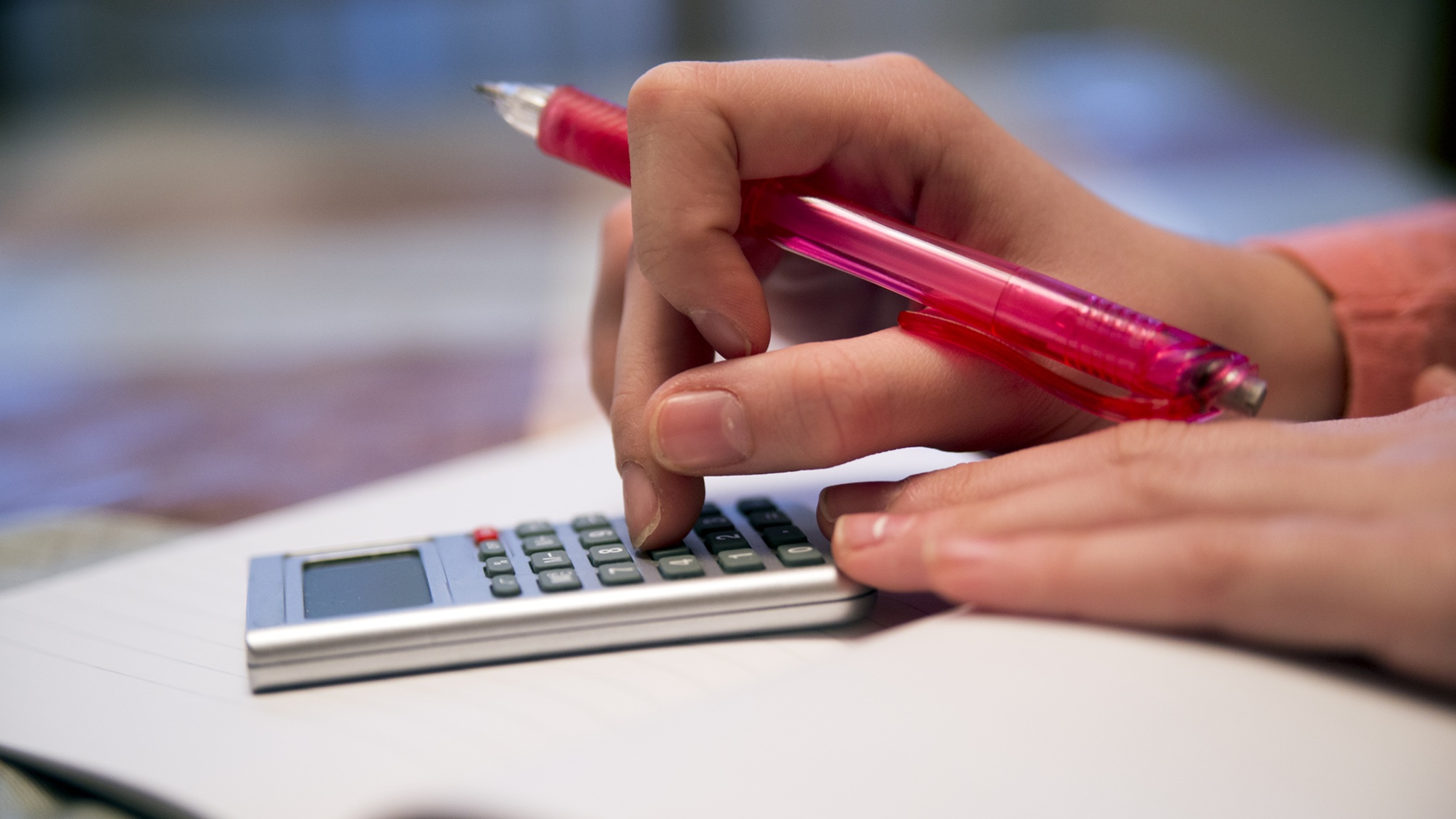 Une adolescente utilise une calculatrice, seules ses mains sont visibles.