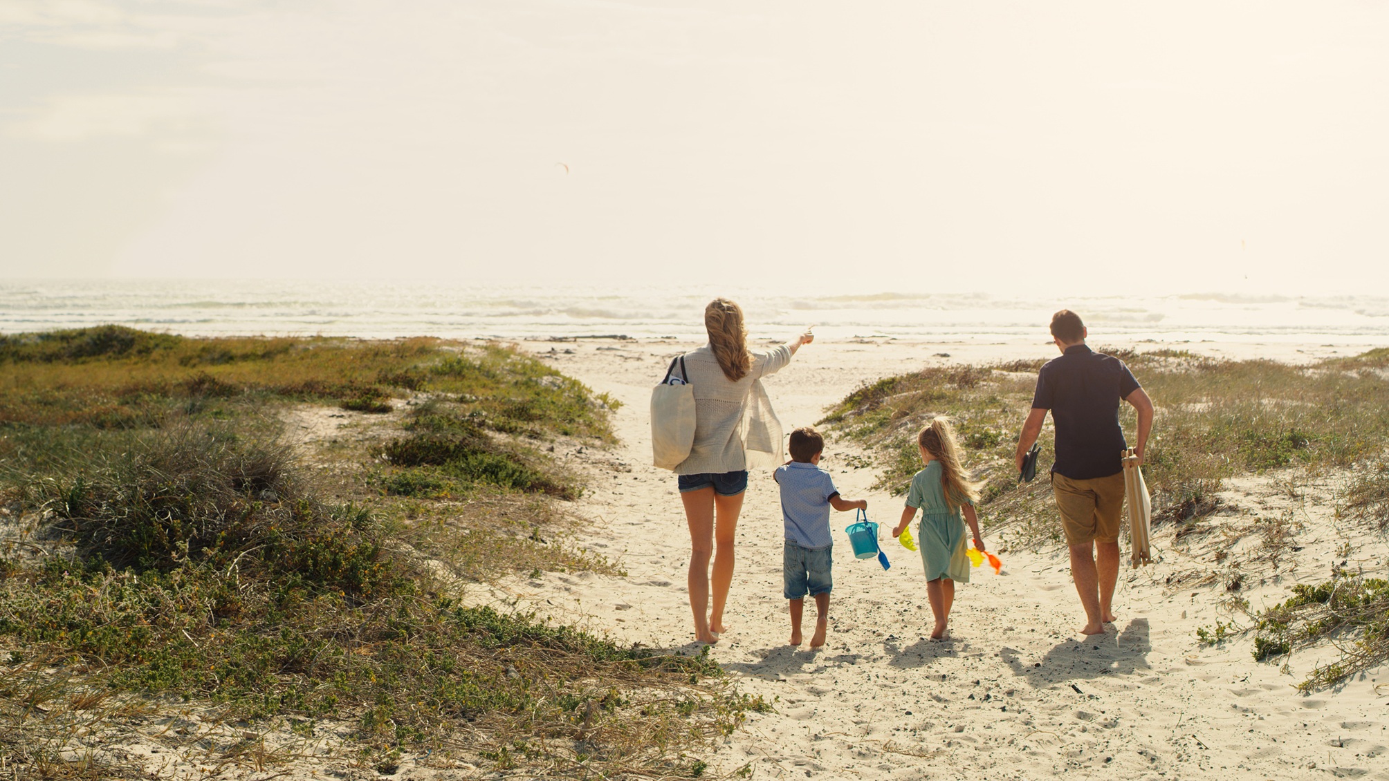 Une famille de quatre personnes se dirige vers la plage.