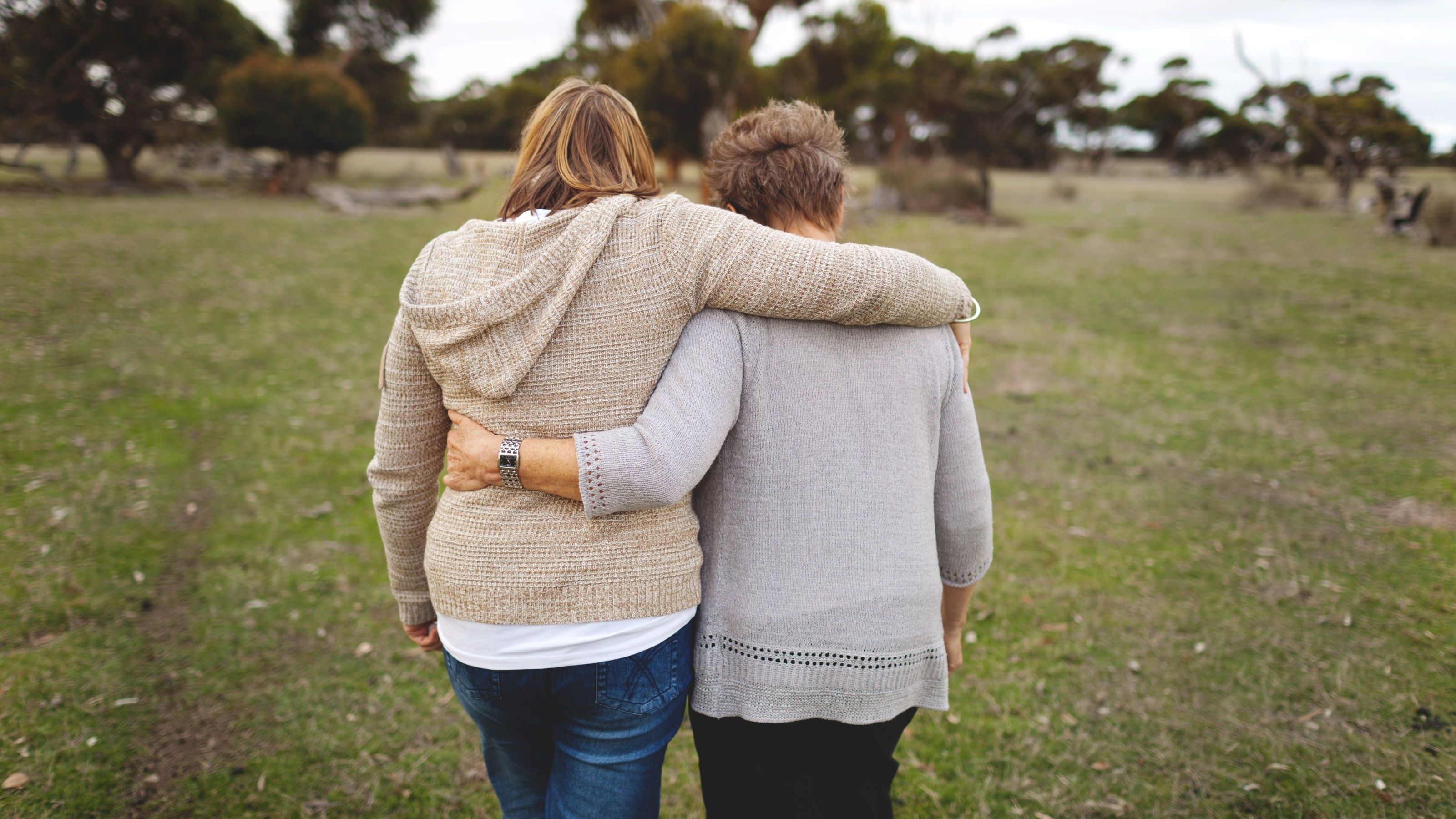 Une femme adulte et sa mère marchent les bras autour de l’autre à l’extérieur.