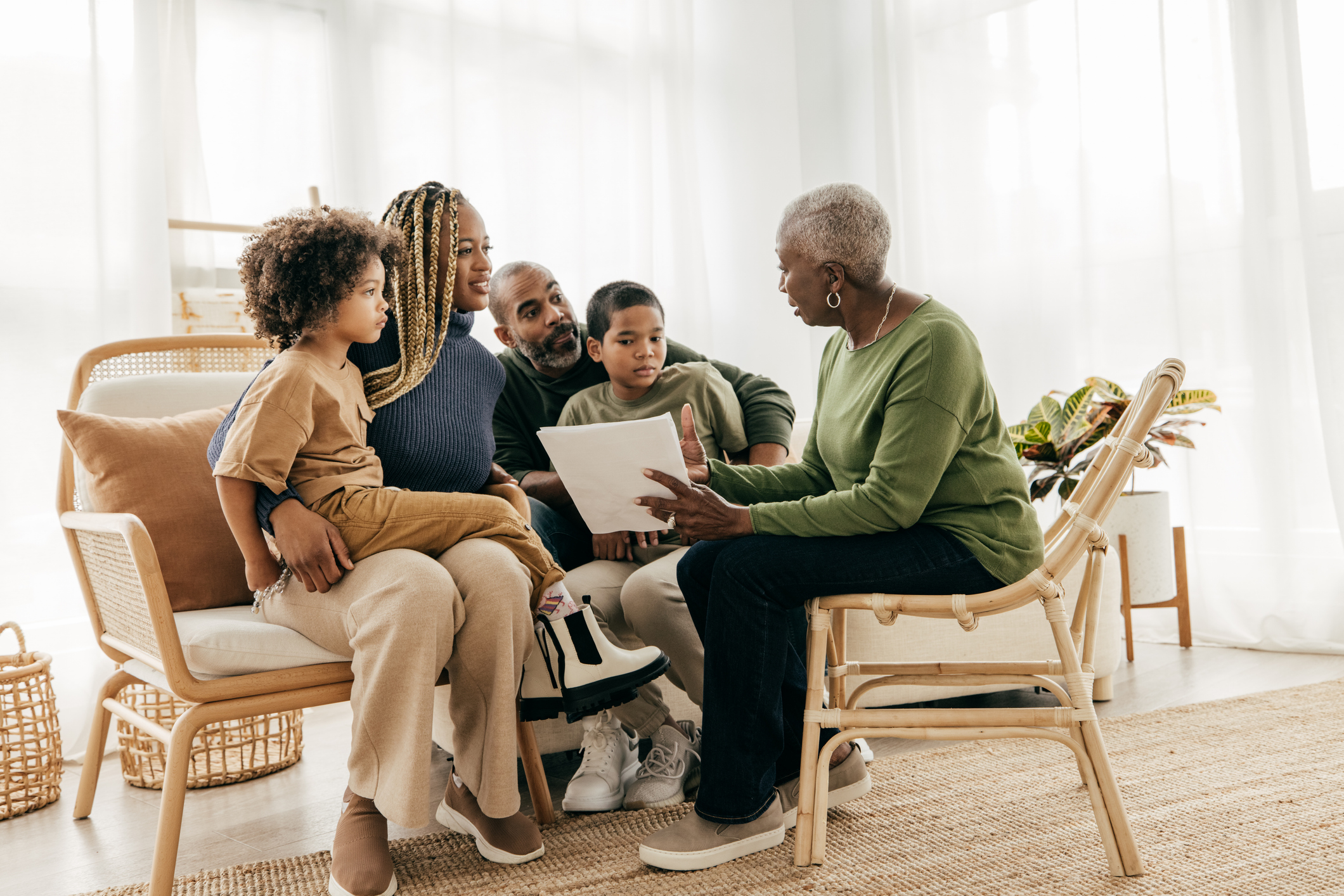 Une femme âgée examine les documents financiers avec sa famille dans son salon.