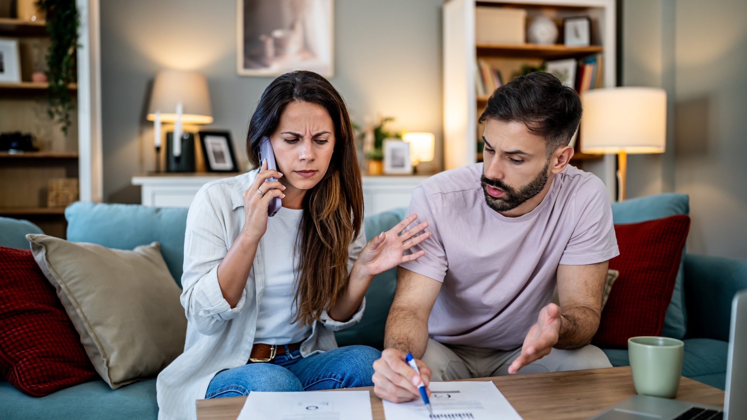 Un jeune couple assis sur son canapé, l'air stressé en parlant d'argent.