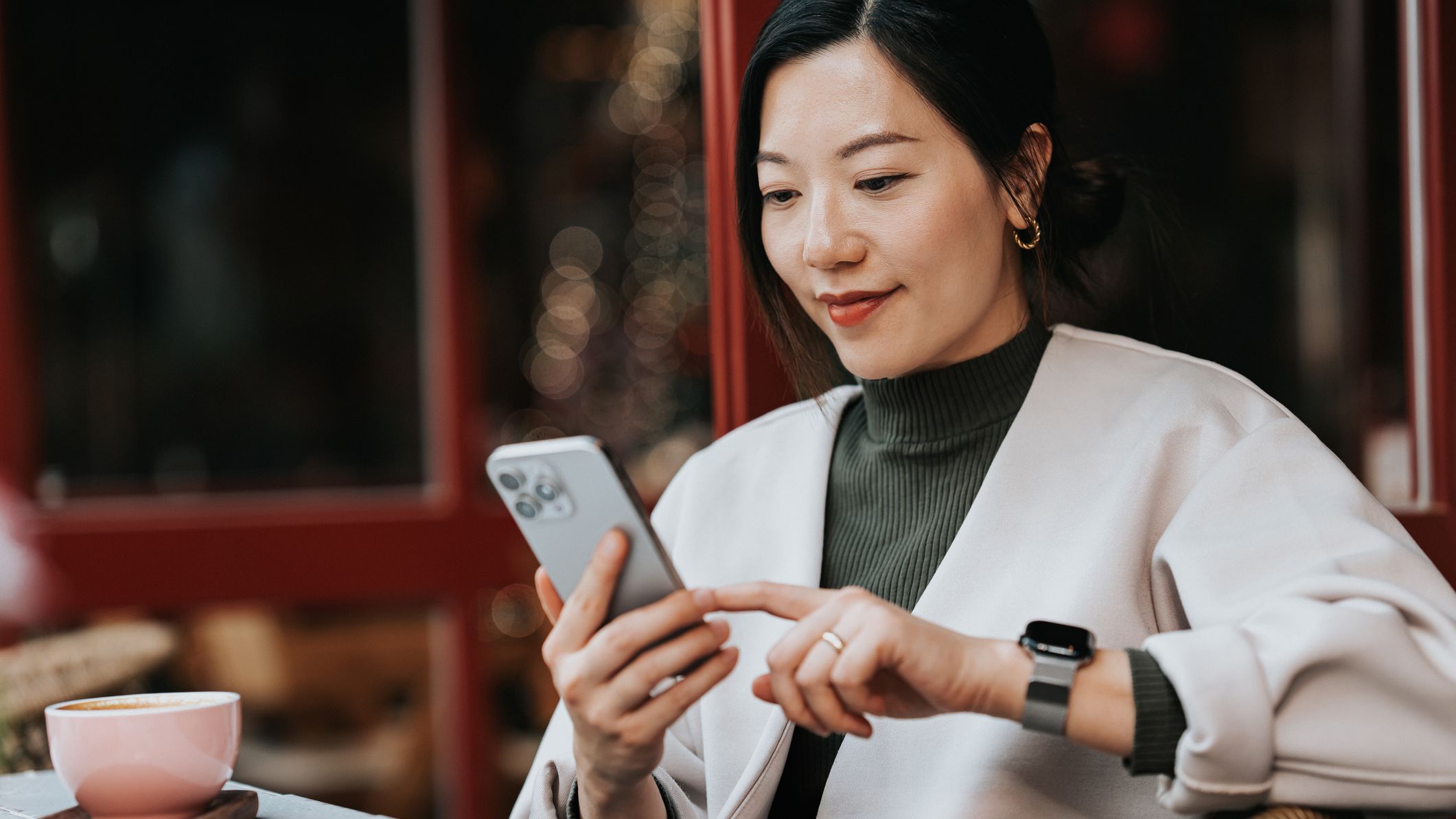 une femme fait défiler son téléphone portable dans un café