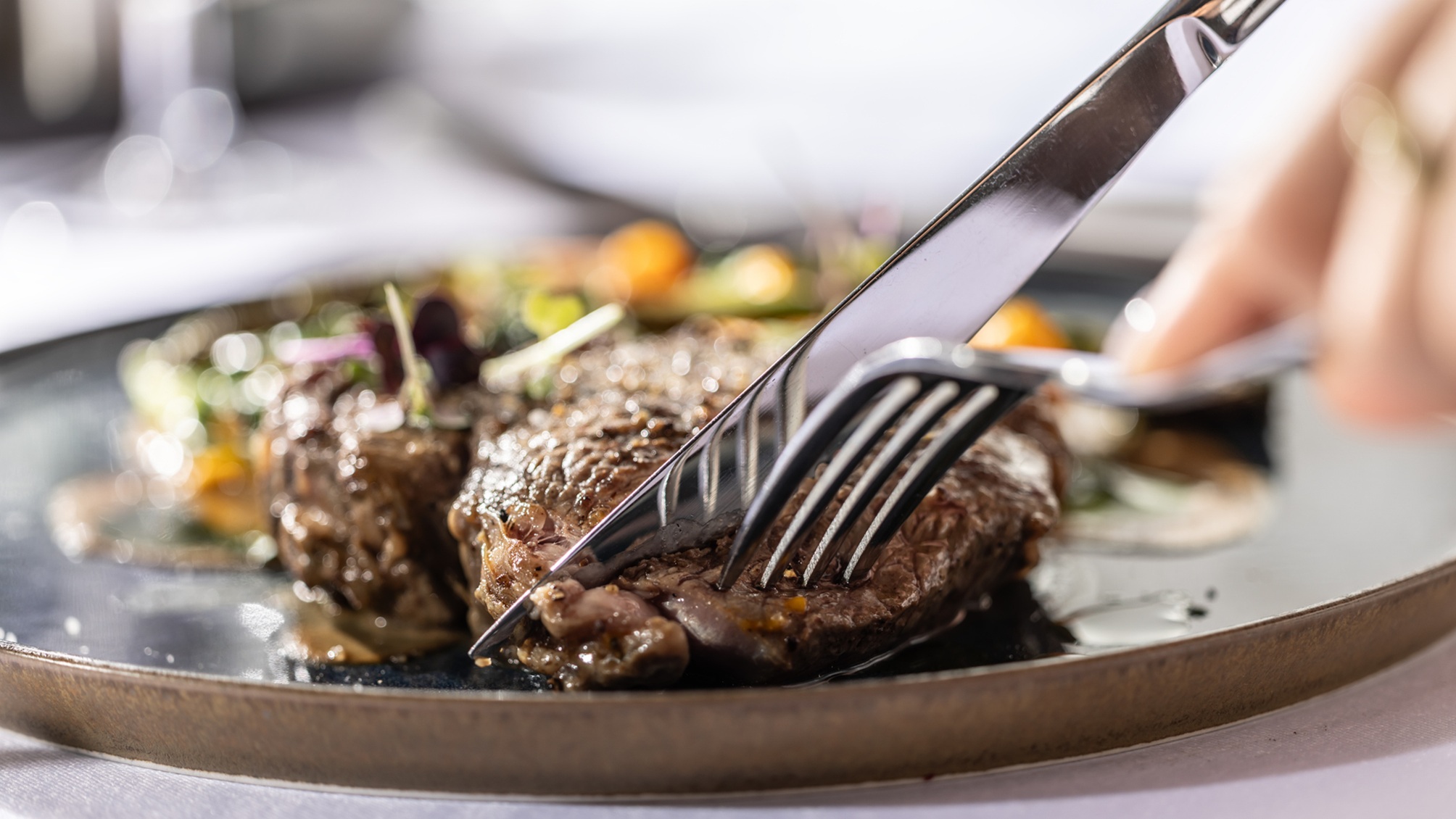 Un couteau et une fourchette creusent un steak sur une assiette.