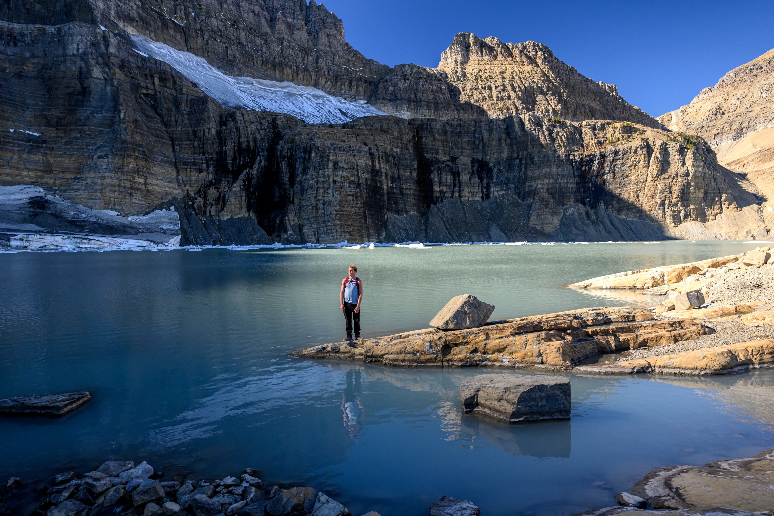 Un randonneur se tient au bord du lac Grinnell, dans le parc national des Glaciers.