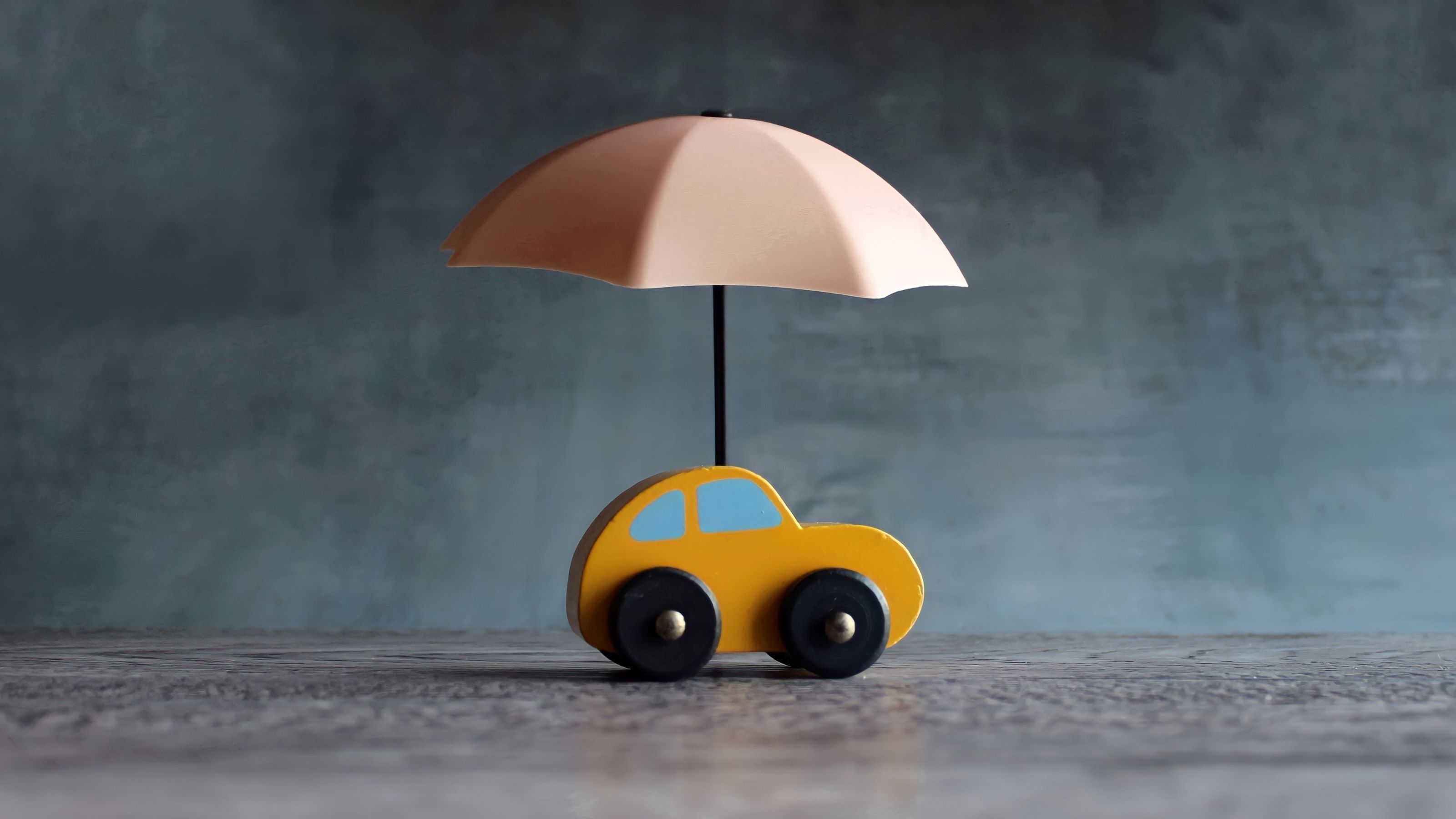 Une petite voiture avec un parapluie dessus, indiquant une assurance automobile.