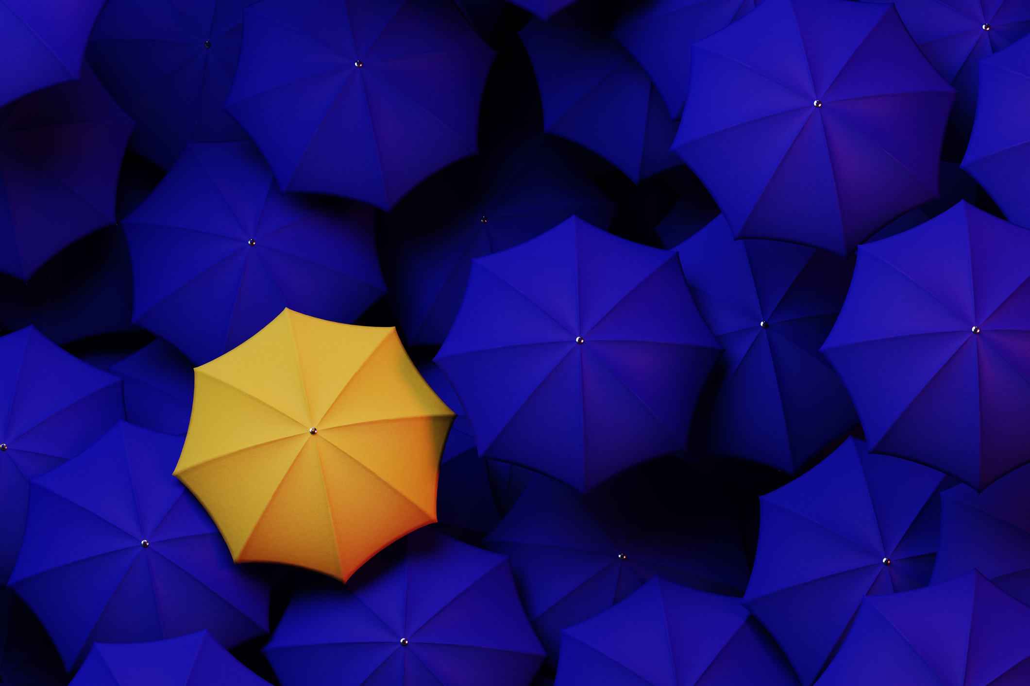 parapluie jaune qui dépasse parmi une mer de parapluies bleus